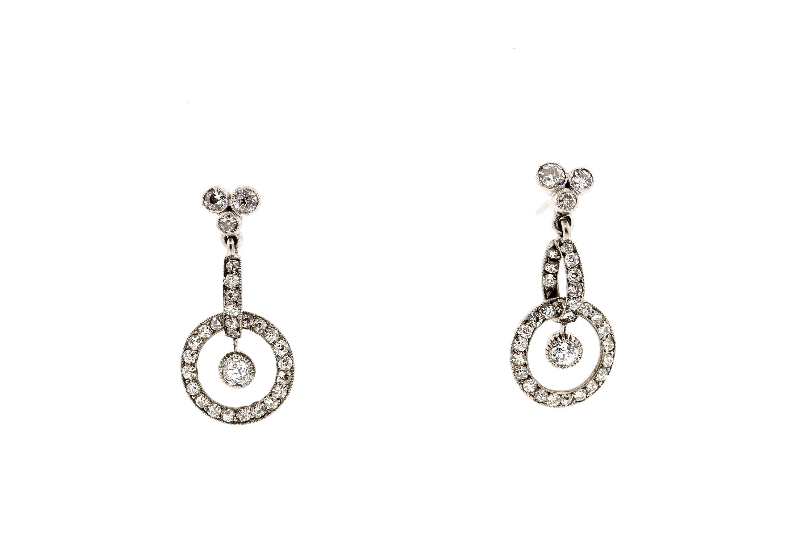 Early 20th Century platinum diamond earrings, circa 1910. These earrings are a pretty design, with a trefoil on top and two connecting dimensional loops on the bottom. They are set with 64 old European and single cut diamonds weighing approximately