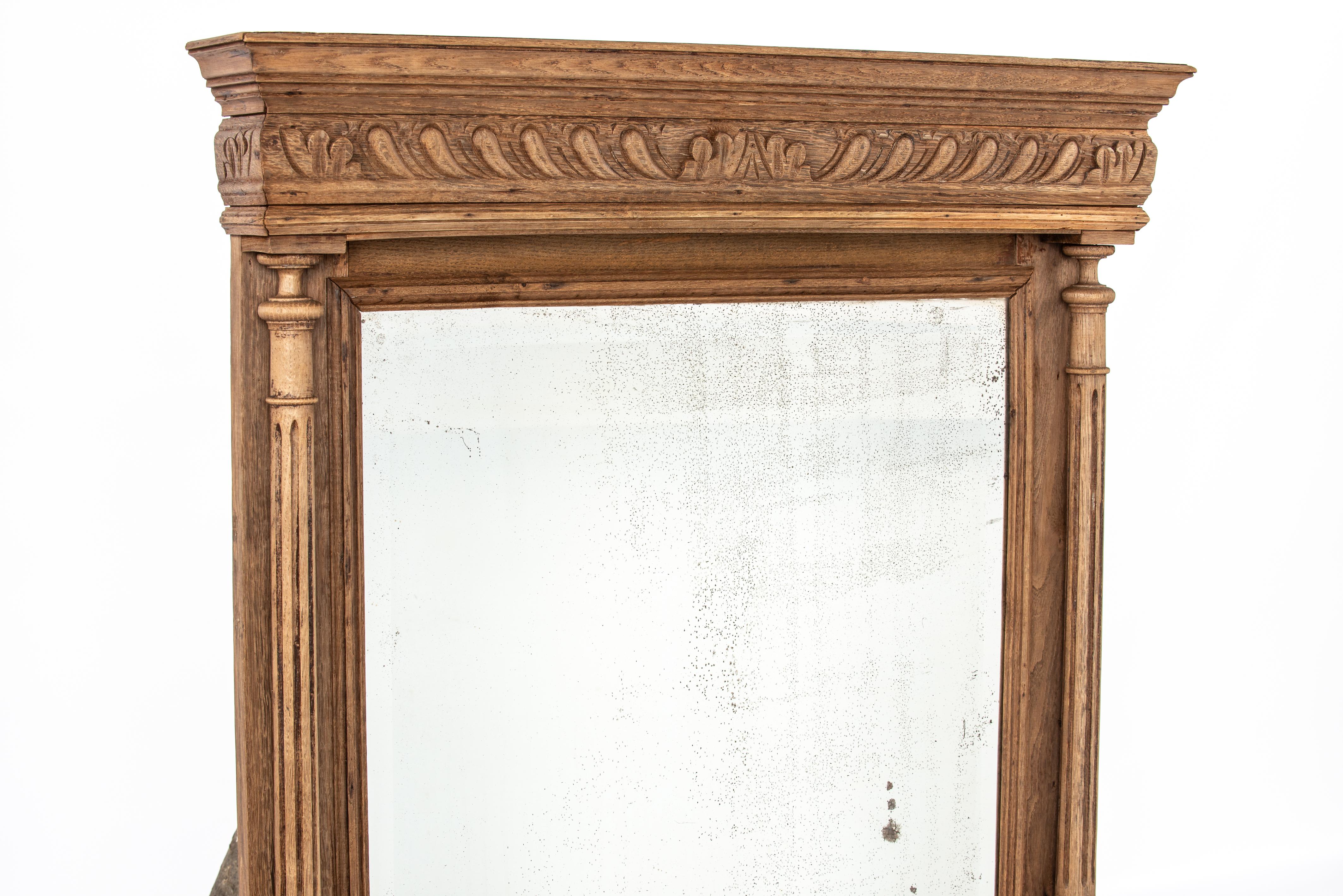 On offer here is an antique solid oak Henri Deux mirror that was made in northern France in the early 20th century. It was elaborately decorated with two handsome turned columns flanking the glass. Above a gadrooned frieze ending in acanthus. The