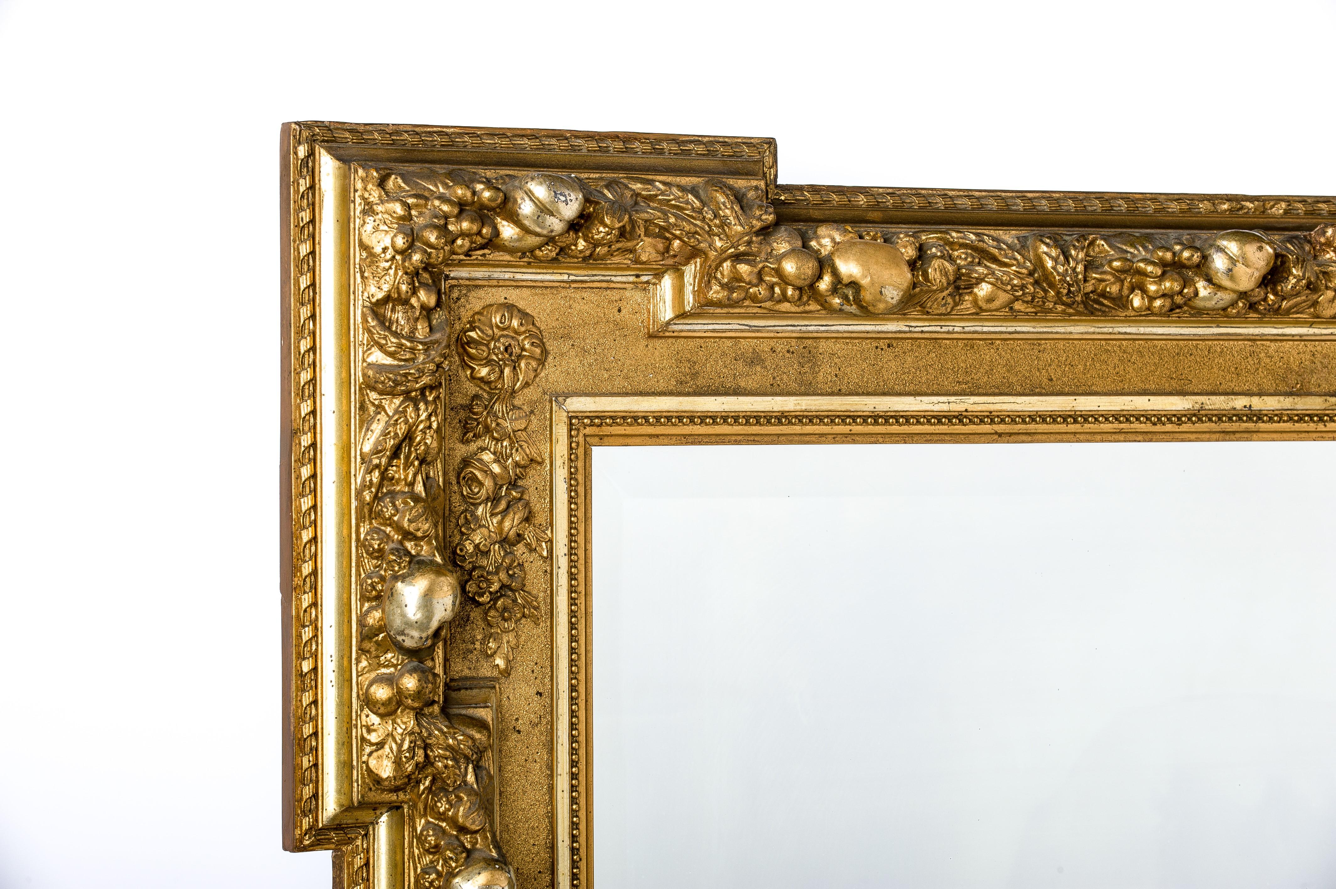 This beautiful antique French rectangular overmantle mirror was made in Northern France in 1905. 
The mirror is elaborately decorated with fruits of the harvest. It shows plums, pears, apples, grapes, blackberries, cherries, and grain. 
The mirror