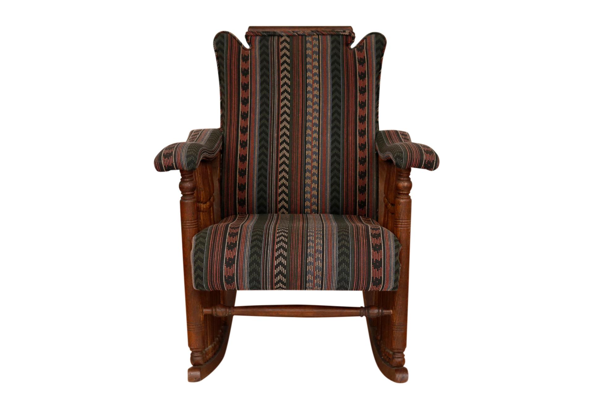 An early American “Brewster” style rocking chair with contoured arms supported with ten spindles on each side. The seat back is a solid panel with a flat crest rail, upholstered in a rich striped kilim fabric.