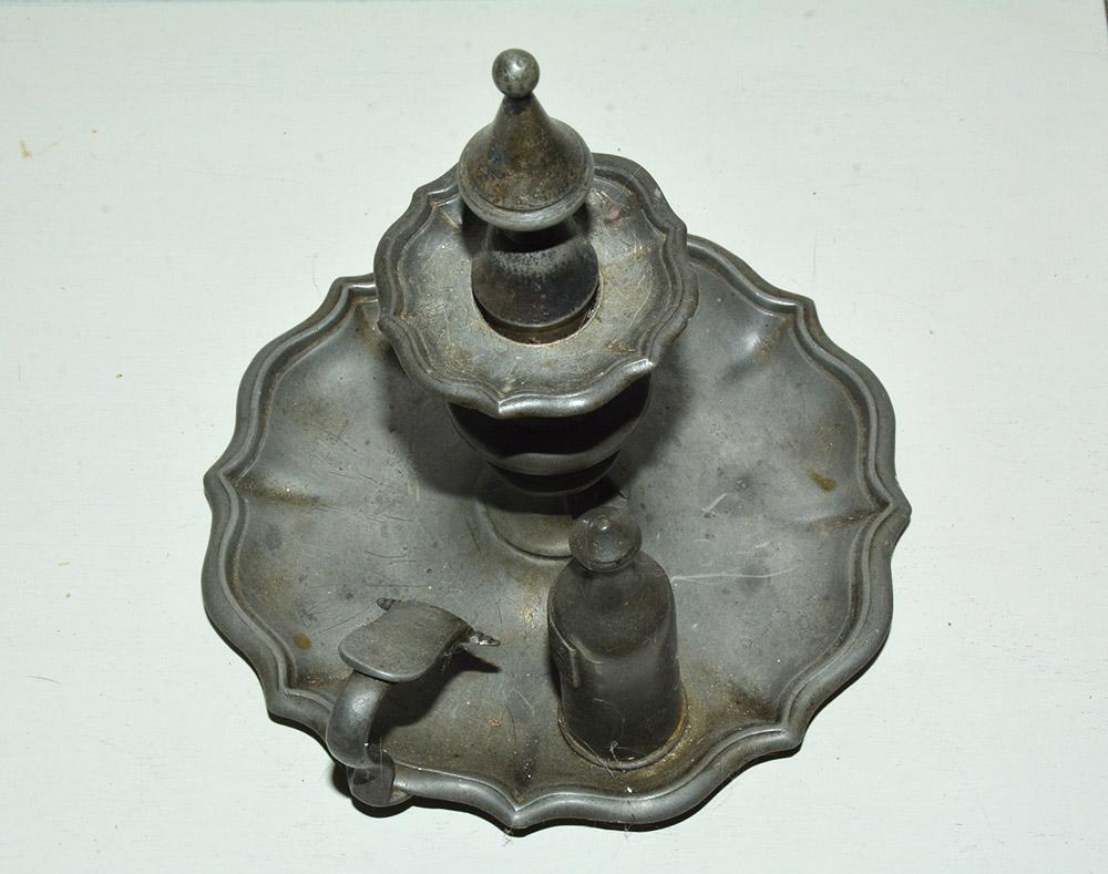 A fine and impressive antique pewter chamber candlestick has a plain round form with scalloped pie shaped edge. The domed center of the plain well is surmounted with a baluster shaped capital also the finial shaped snuffer that sits on top of the