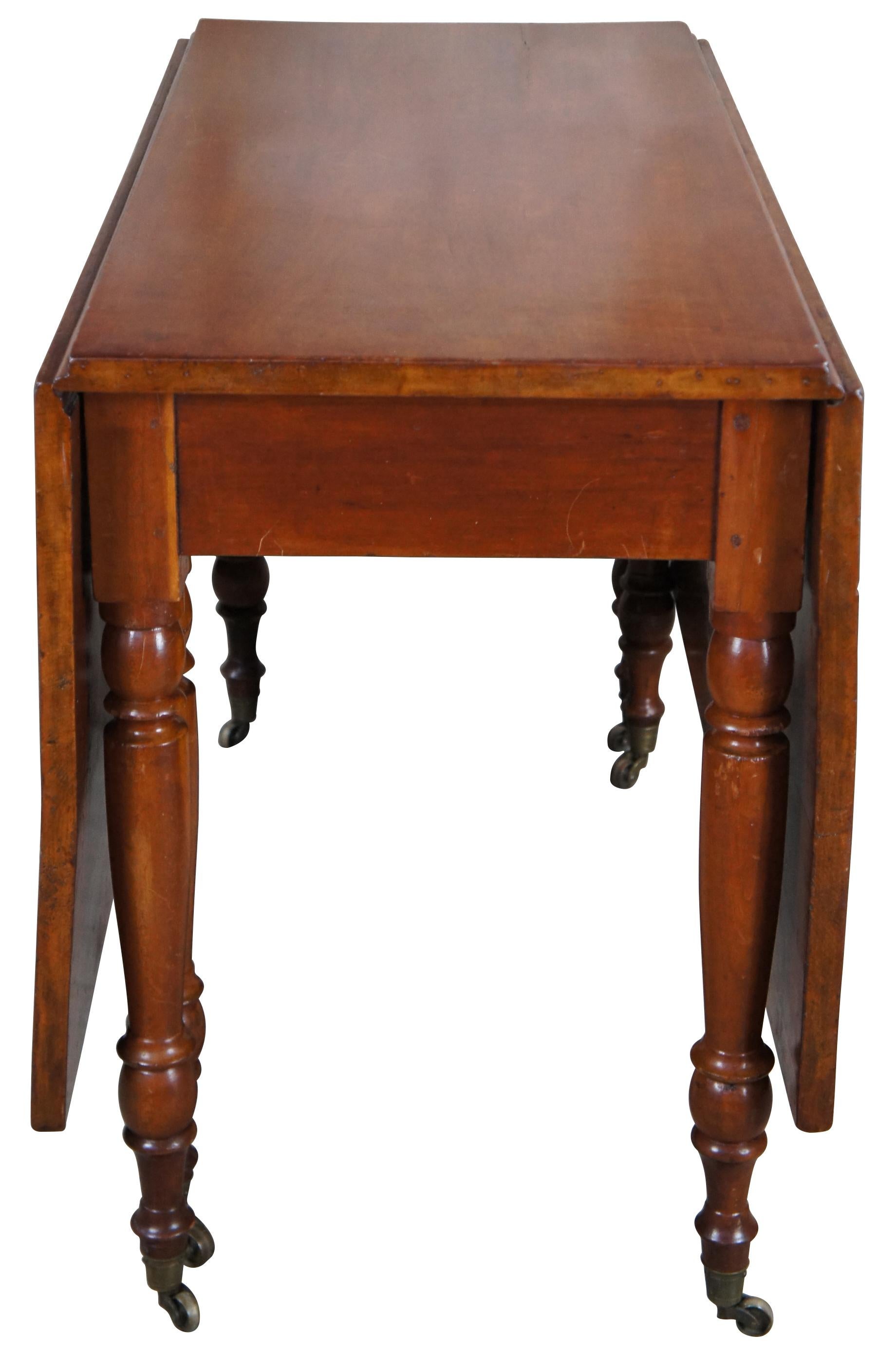 American antique 19th century dining or console table. Made from solid cherry with long drop leaves and tuned legs leading to brass casters. 

Measures: 44
