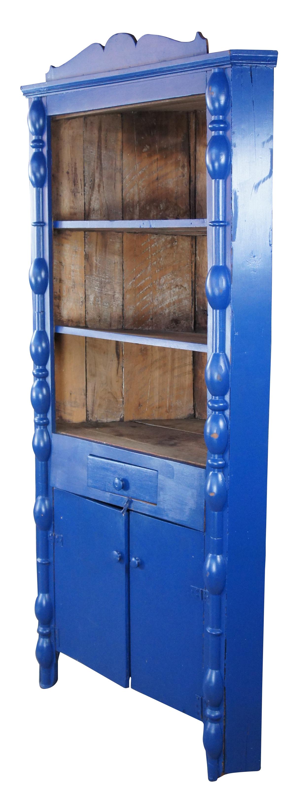 Antique Early American style blue painted farmhouse corner cupboard or cabinet, circa 1900s. Features quarter cut turned columns with three shelves, one drawer and lower cabinet. Measure: 79