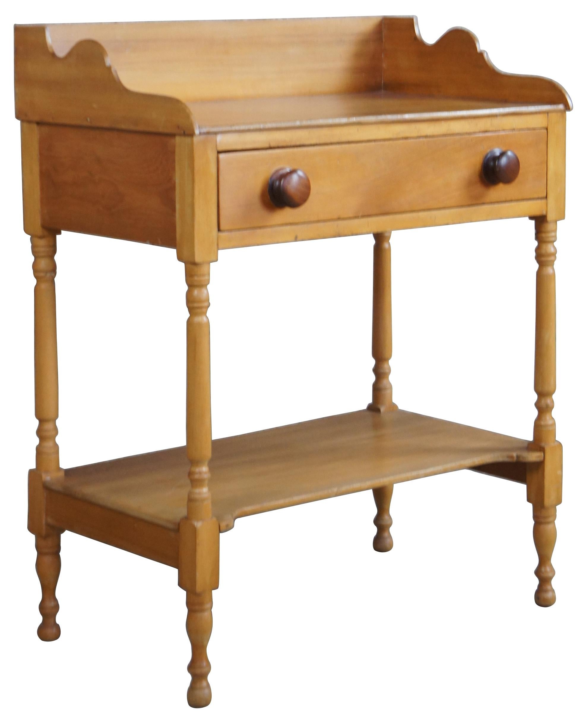 Antique early American washstand or side table. Made of pine with a single drawer with turned knobs, bottom shelf and a serpentine dovetailed backsplash.
 
Dimensions
26.25