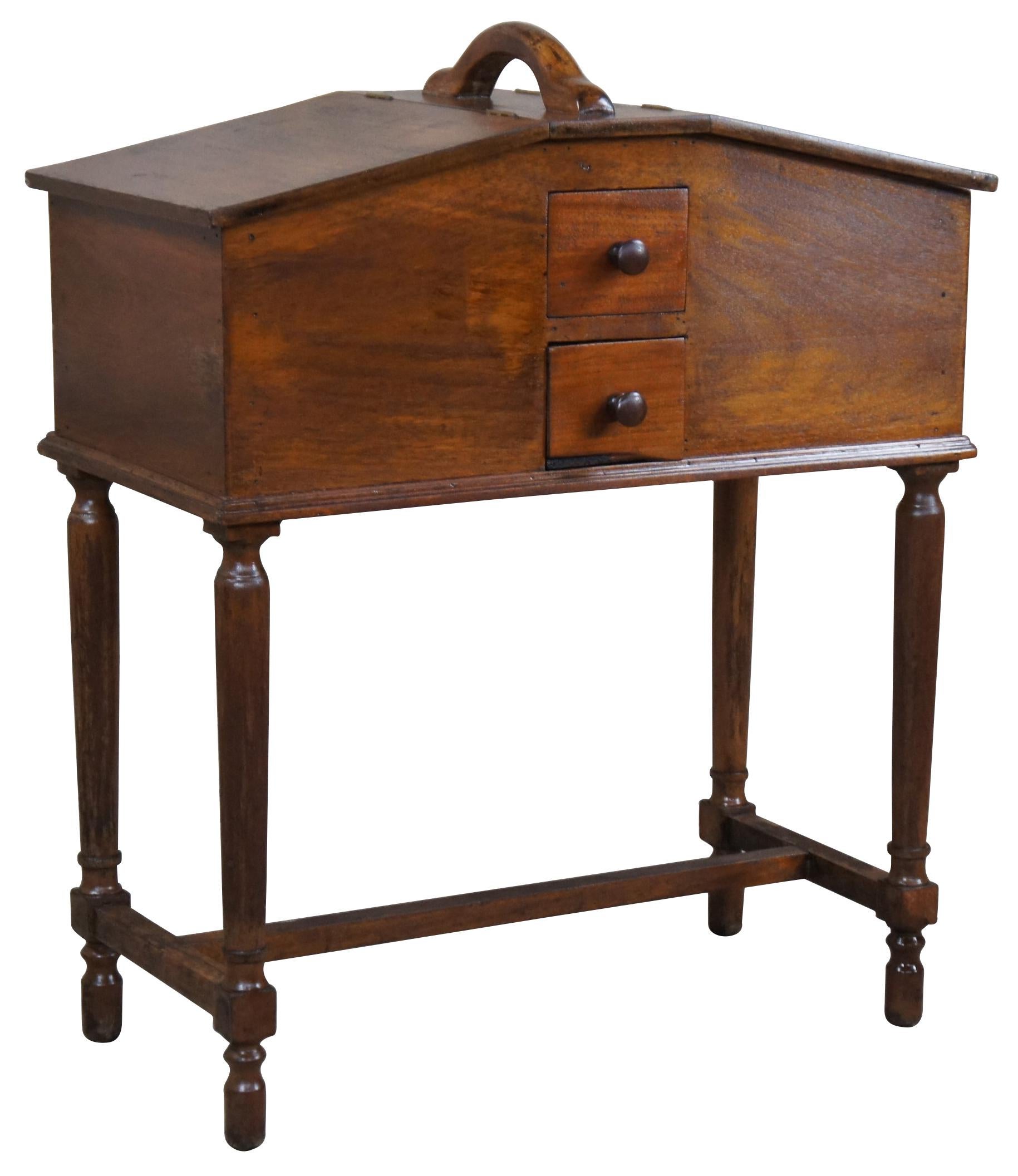 An unusual early 20th century sewing box or stand. Drawing inspiration from William & Mary styling. A rectangular form made from walnut with a house shaped body featuring two lidded boxes for storage, a handle for moving and two petite drawers at