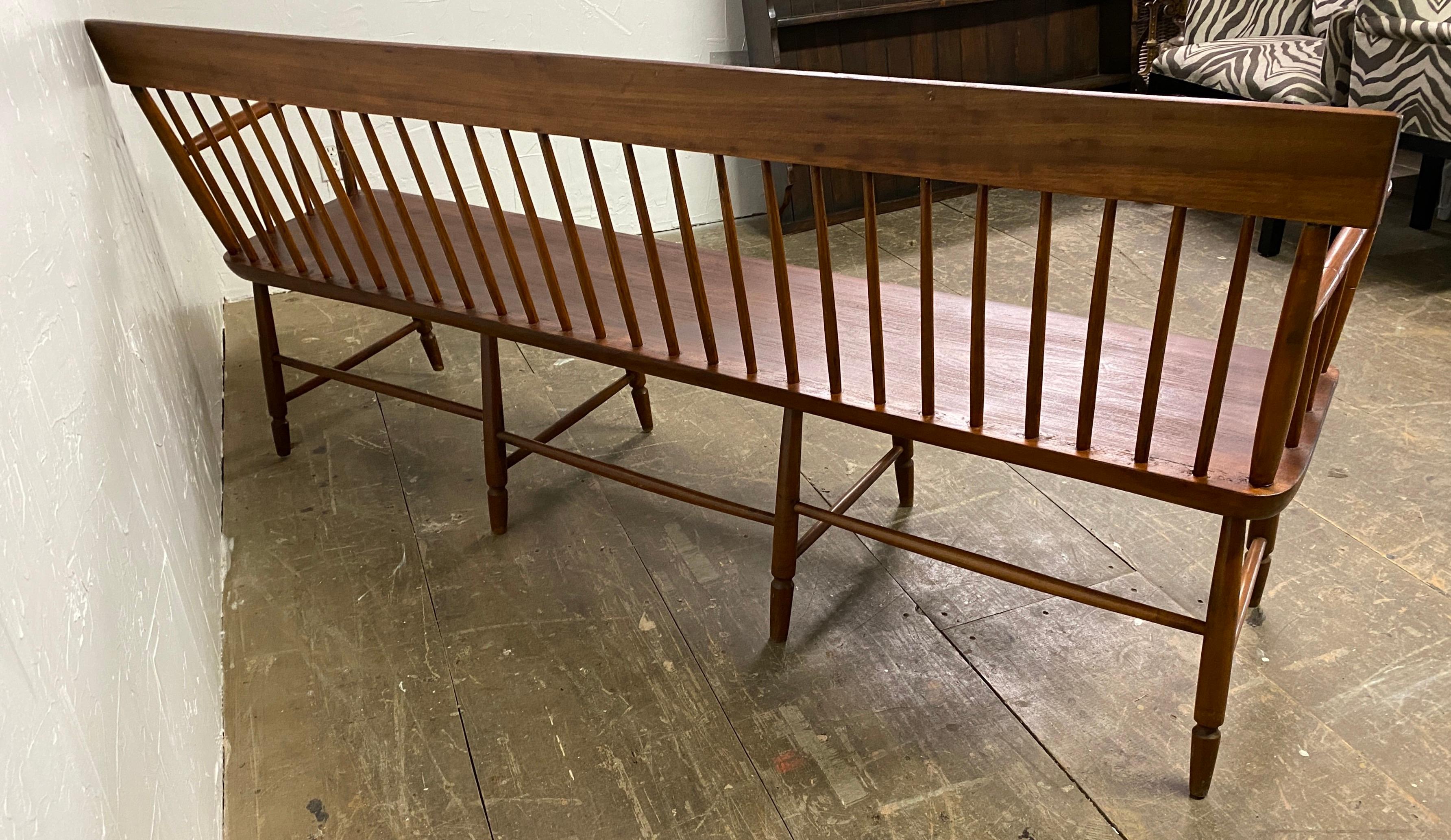 American colonial style spindle bench, features a single back splat with spindles and arms over a plank seat the bench is supported by eight legs connected by splindled stretcher. Great for use as a hall bench, mudroom bench or extra dining room
