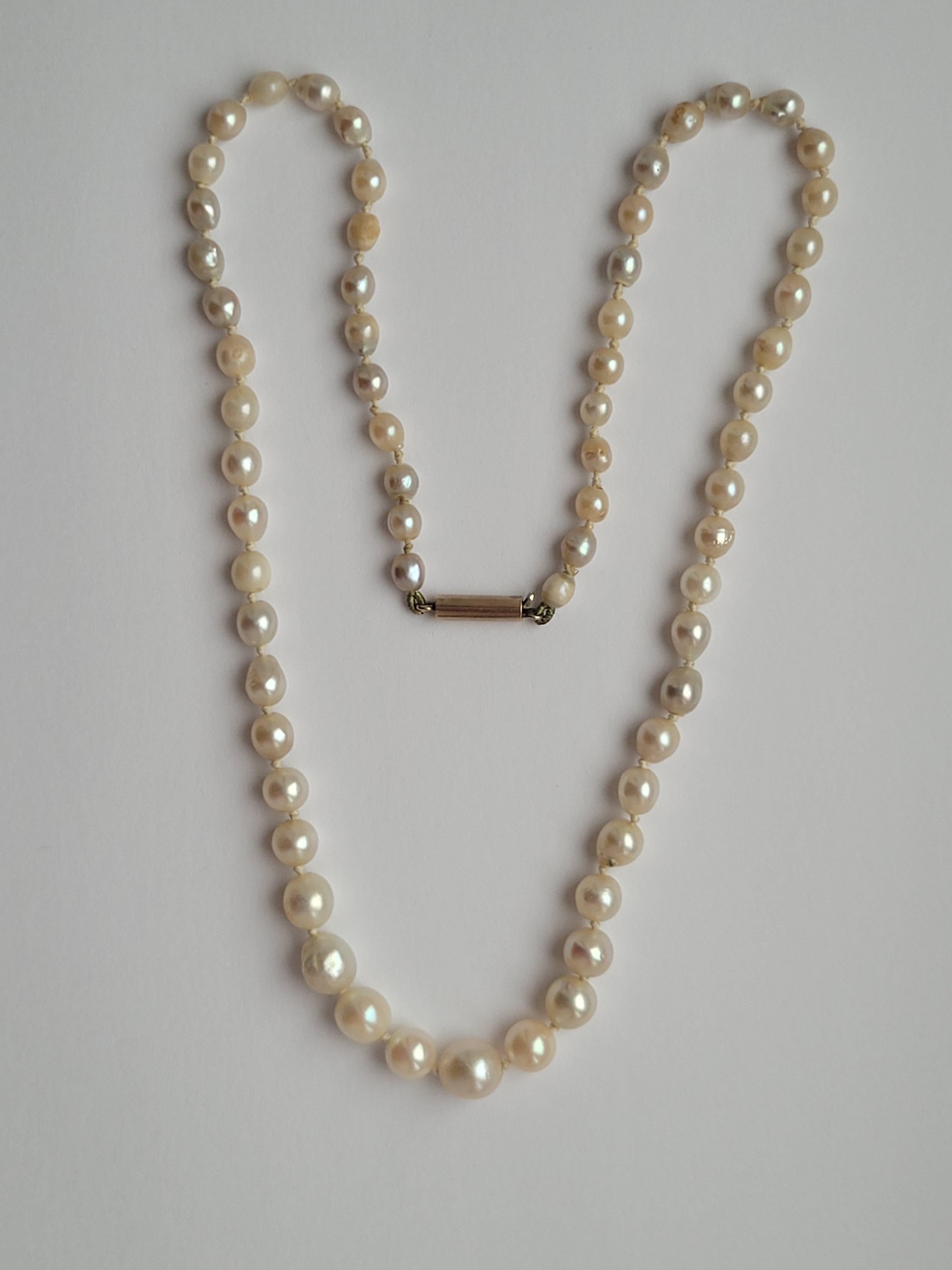 An Antique early 1900s Cultured Pearl necklace with a gold barrel clasp. The luster of the pearls varies from cream to grey. English origin.
Pearls from 4mm to 7mm.
Total length including clasp 17