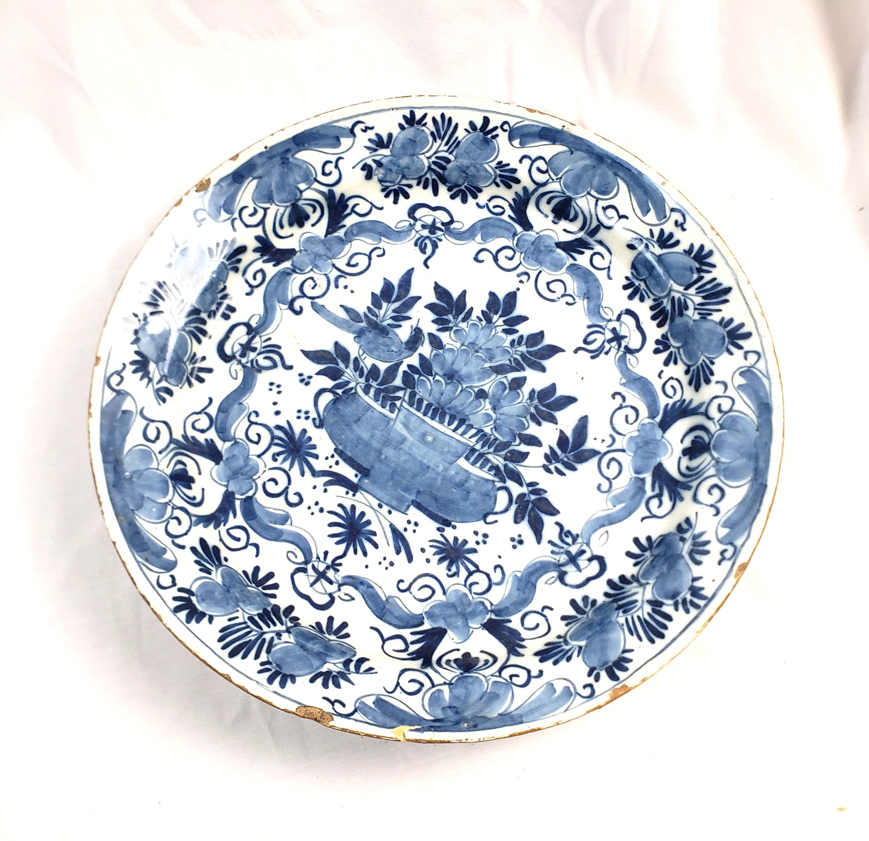 This antique charger is signed by an unknown maker, but presumed to have originated from the Netherlands and date to approximately 1750 and done in the period Delftware style. This early charger is composed of ceramic with a white ground and