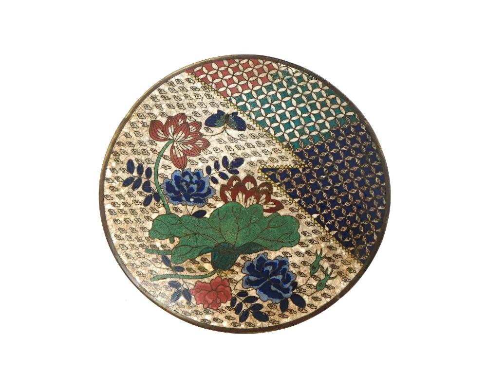 An antique Japanese, Meiji era, enamel plate.

The interior of the plate is adorned with a polychrome enamel image of a butterfly in blossoming flowers surrounded by a cloud motif, reticulated floral and geometrical ornaments made in the Cloisonne