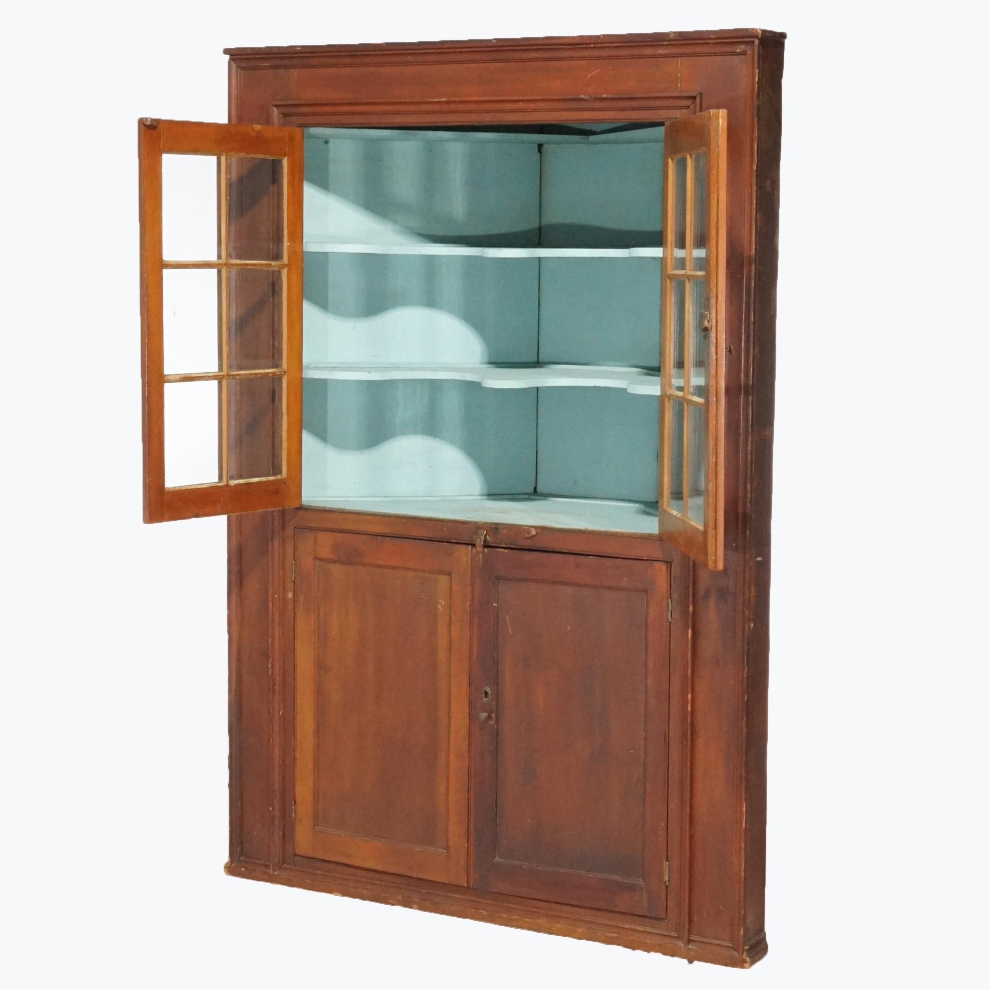 An antique Pennsylvania corner cupboard offers cherry construction with upper having double six-pane doors opening to shelved interior over lower blind cabinet c1820

Measures- 74.75''H x 51.25''W x 22.5''D
