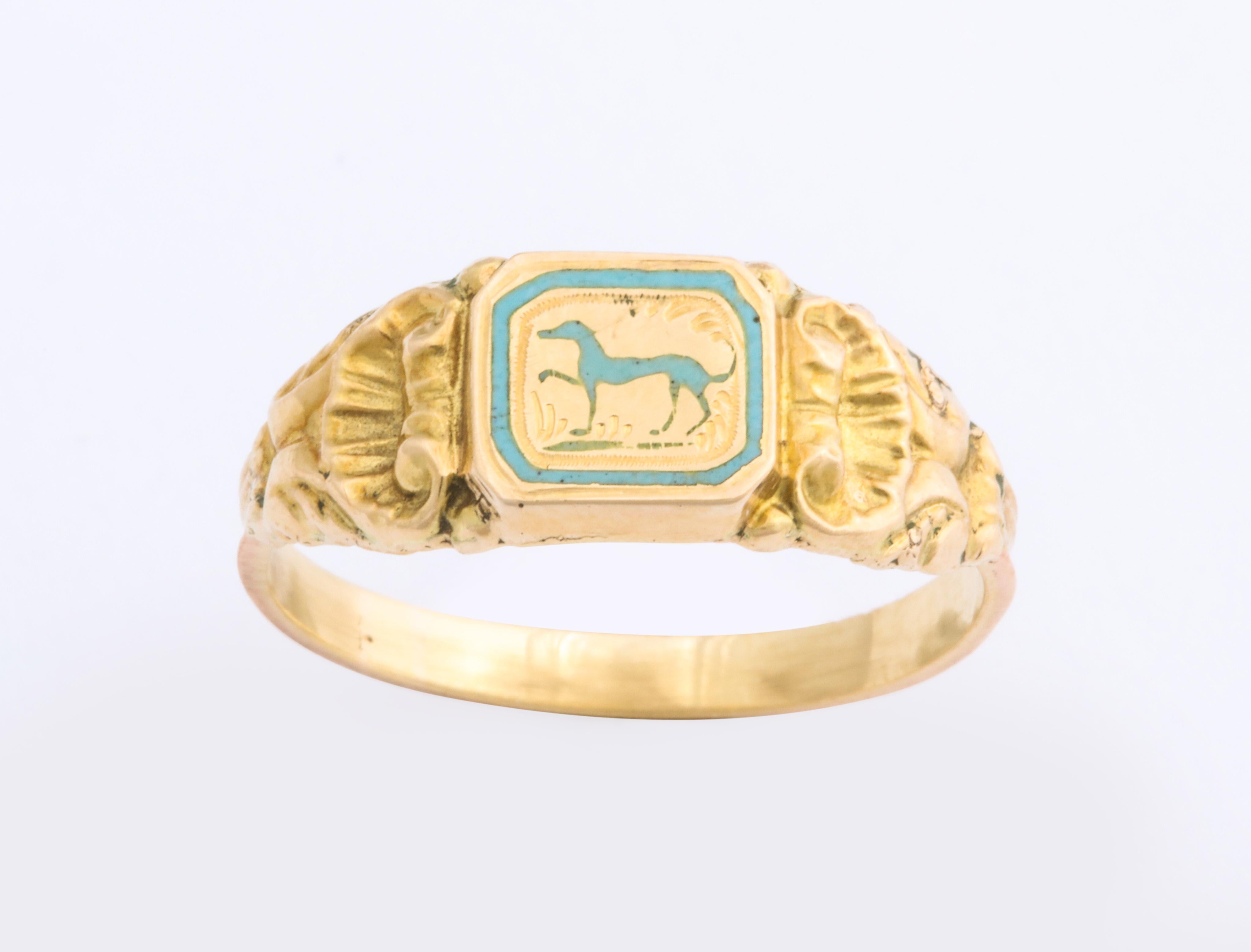 A French 18 Kt gold ring c. 1840, likely the only one ever made, depicts a greyhound or whippet in pale aqua with one leg gracefully raised in a prance. and head erect. The dog is bordered by an aqua frame that strengthens the design. Engraved marks