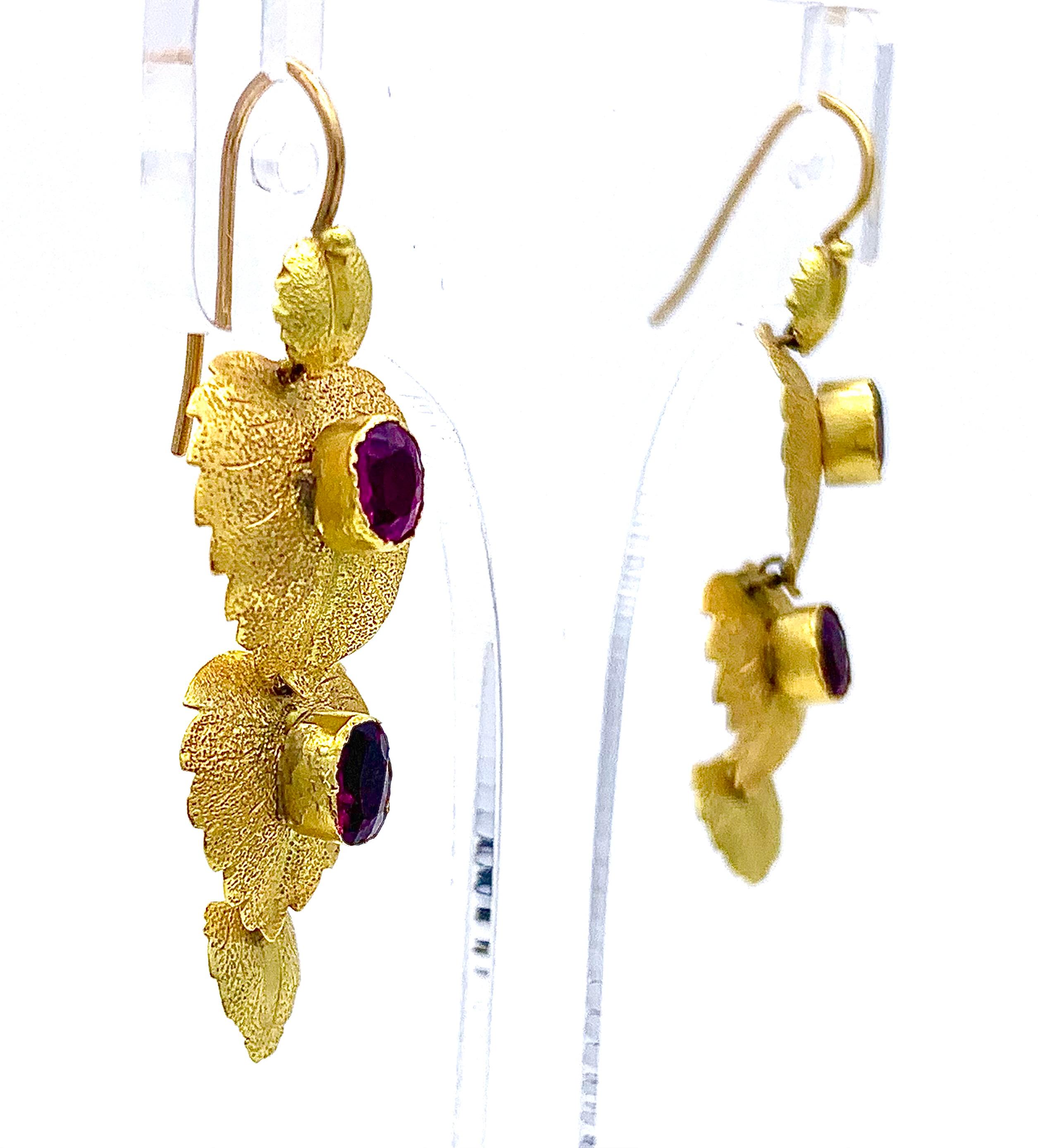 Three delicately designed leaves make up these rare and delicate  dangle earrings.  The earrings were handcrafted in 1845 ca out of 15 karat gold. The leaves have a delicately textured surface. 
Four of the leaves are set with oval almandine garnets