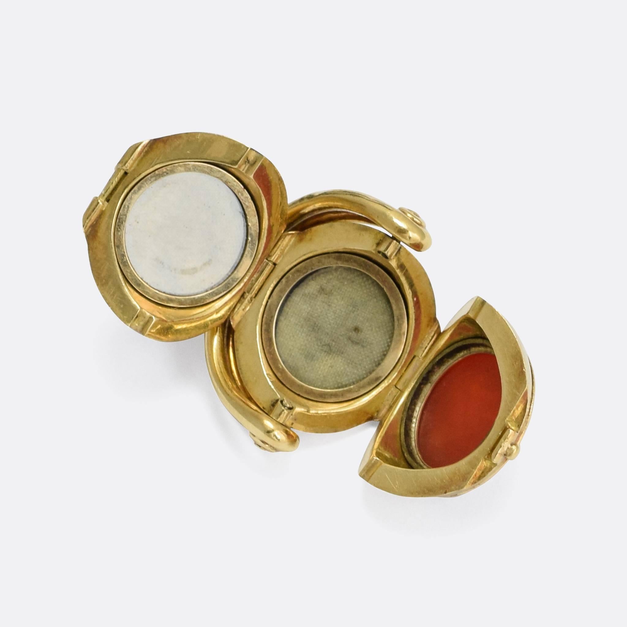 A cool and unusual antique spinner fob featuring three round intaglio panels. The piece also opens up to reveal a secret locket compartment. On the panels are two monograms (MK initials in different scripts) as well as an English heraldic crest: a