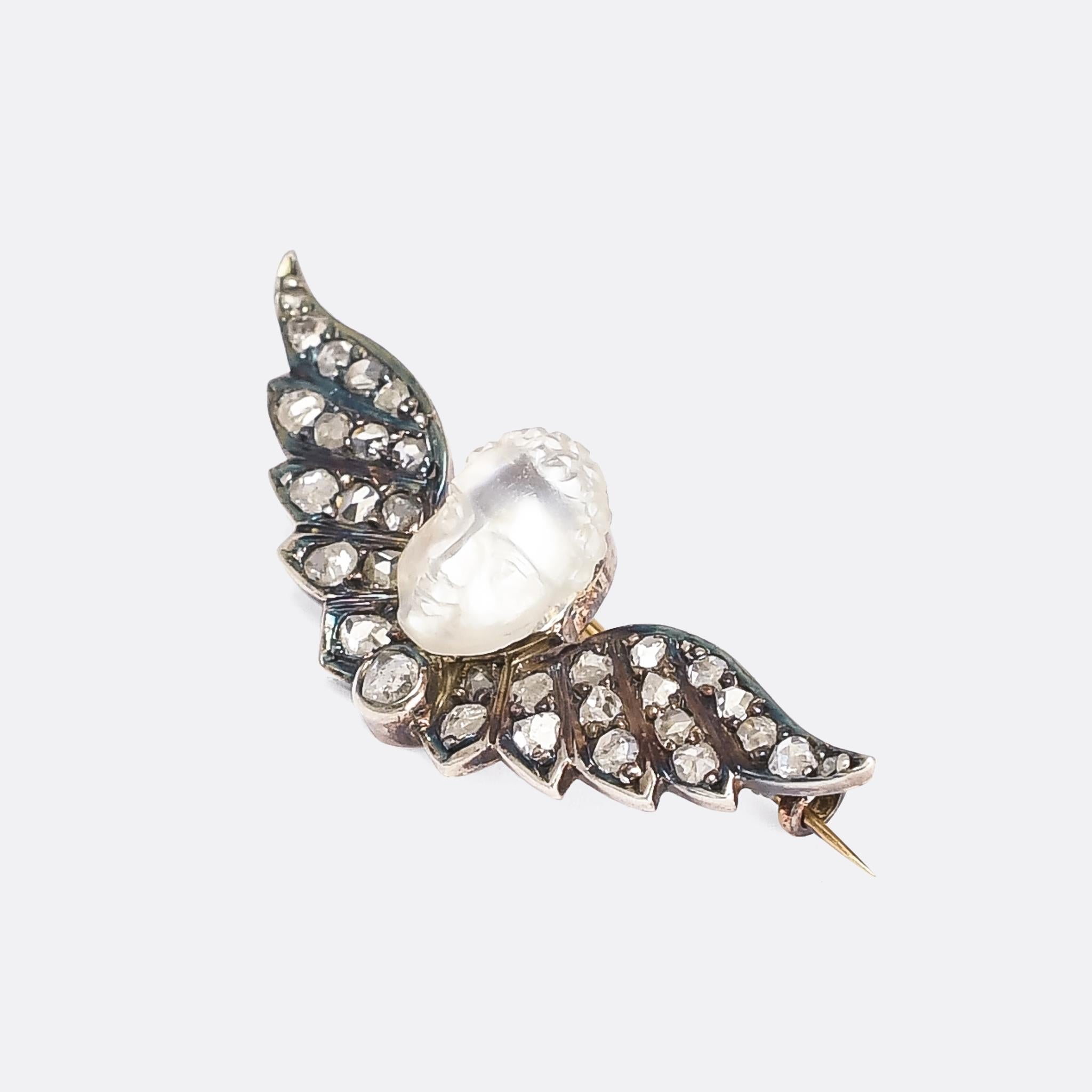 An incredibly rare early Victorian winged man-in-the-moonstone brooch. The wings are set with rose cut diamonds, and it's crafted in 18 karat gold with silver settings. The moonstone face is one of the best we've seen: carved in high relief, with a