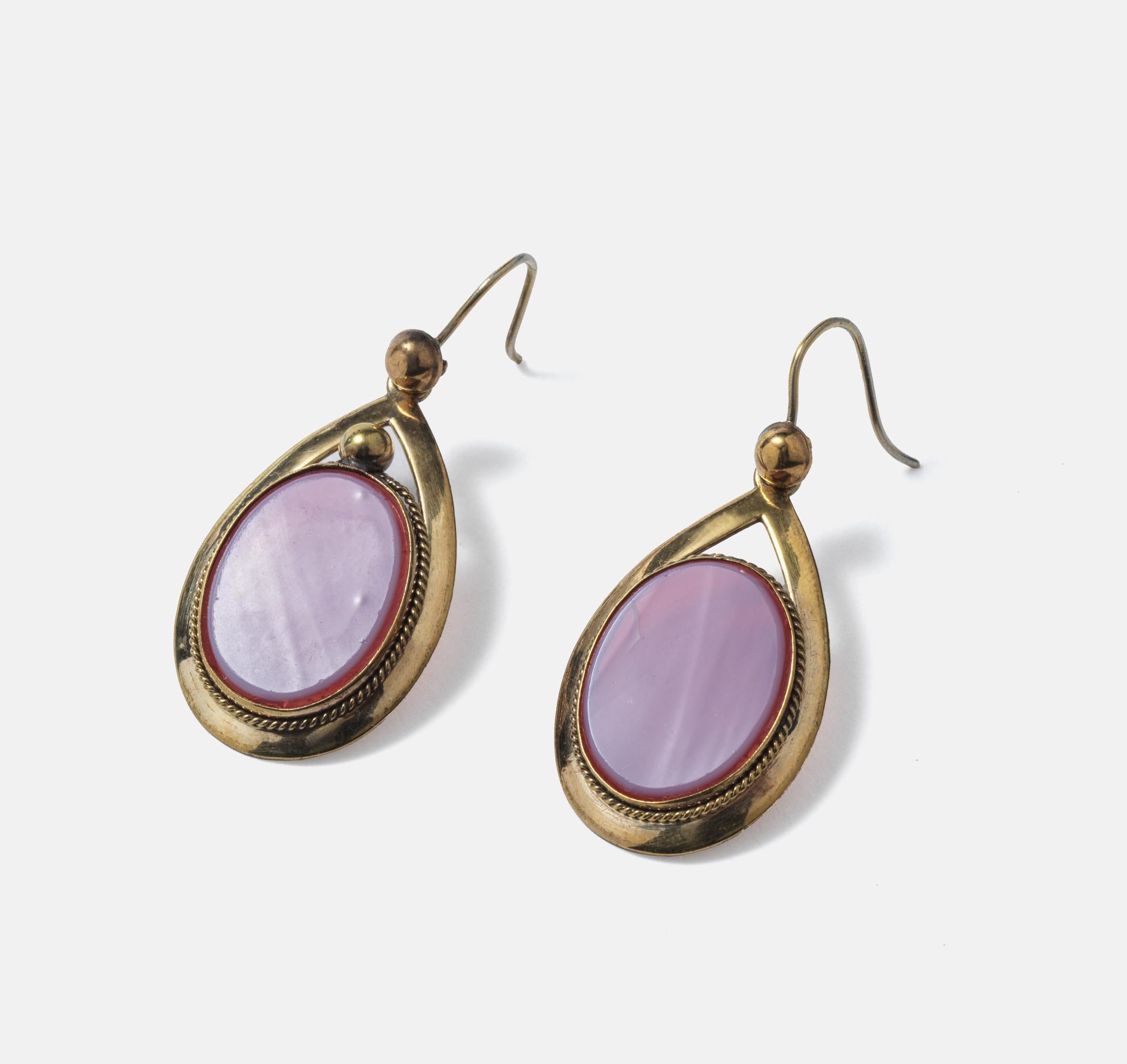 Happy earrings. The metal, tombak, is surrounding pink/purple oval glass pieces. Tombak is a metal alloy made of copper and zink.  It was quite often used in the 19th c to make jewelry.
The handcraft of these earrings is great and the colour of the