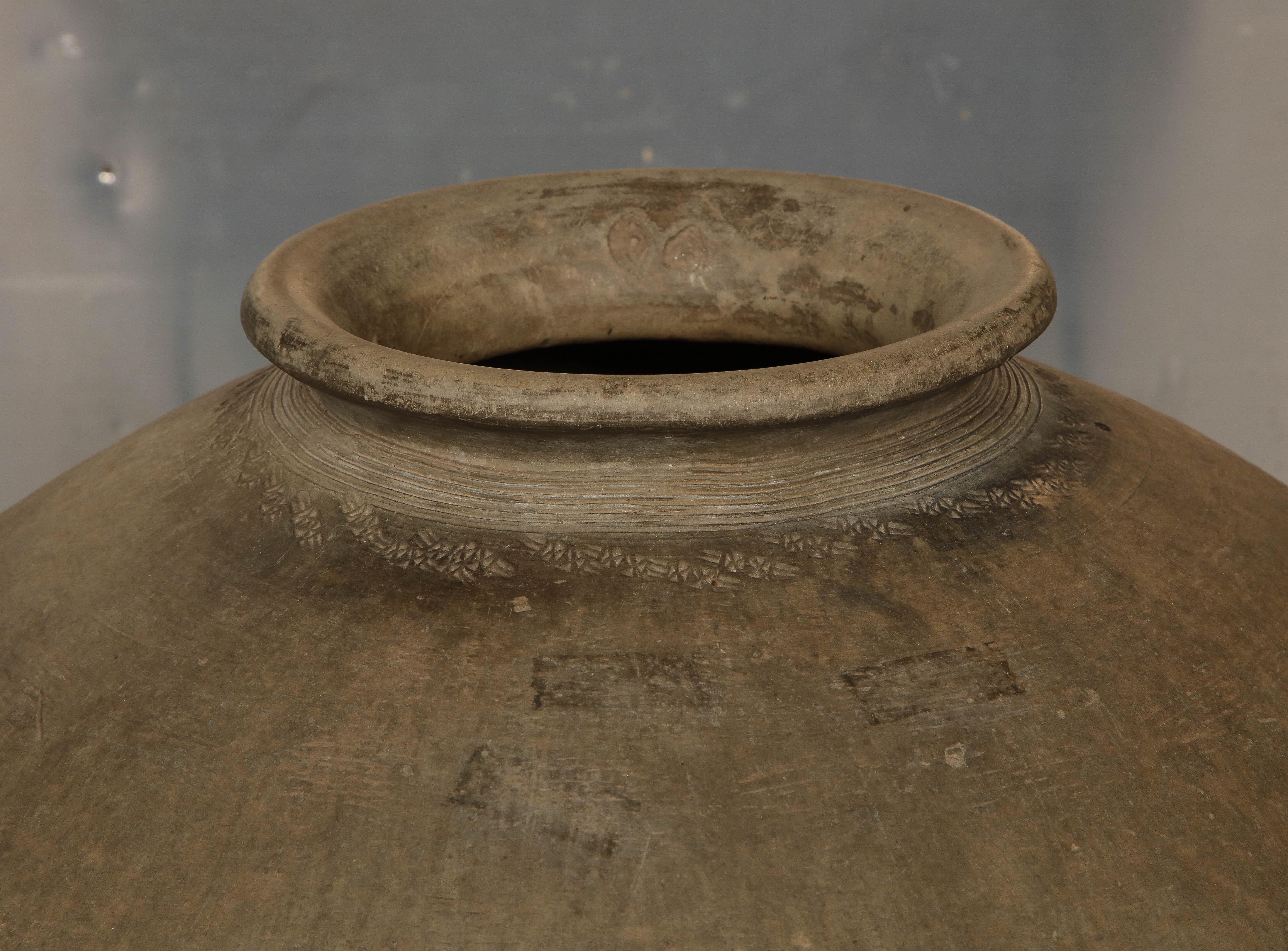 The collar incised with geometric decoration; supported on a wrought iron stand.