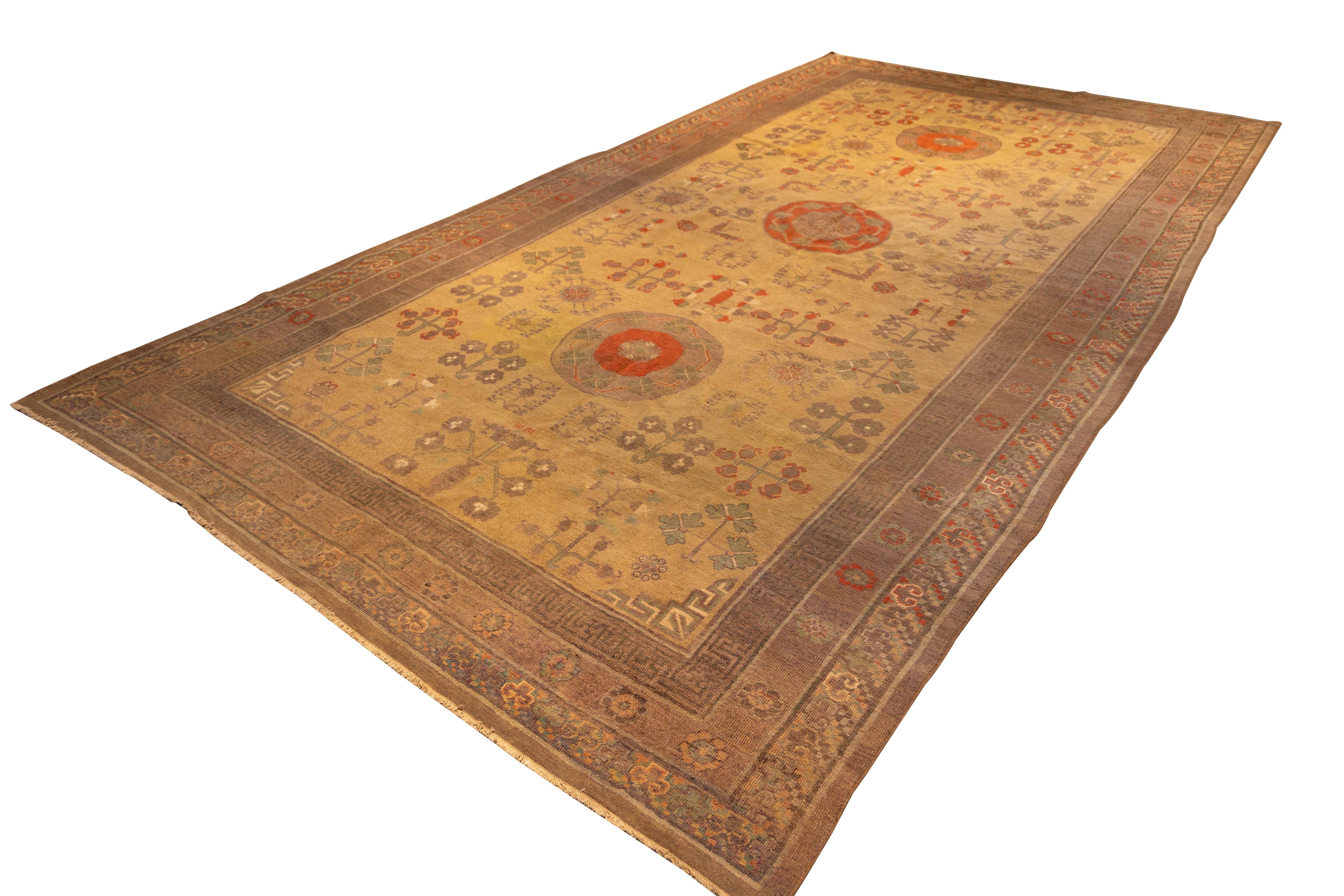 Exceptional example of East Turkestan weaving, this late 19th-century Khotan rug features a unique lattice of medallions and pomegranate-inspired floral motifs in soft brick, apricot, sage, and olive tones on a warm golden field. The repeating