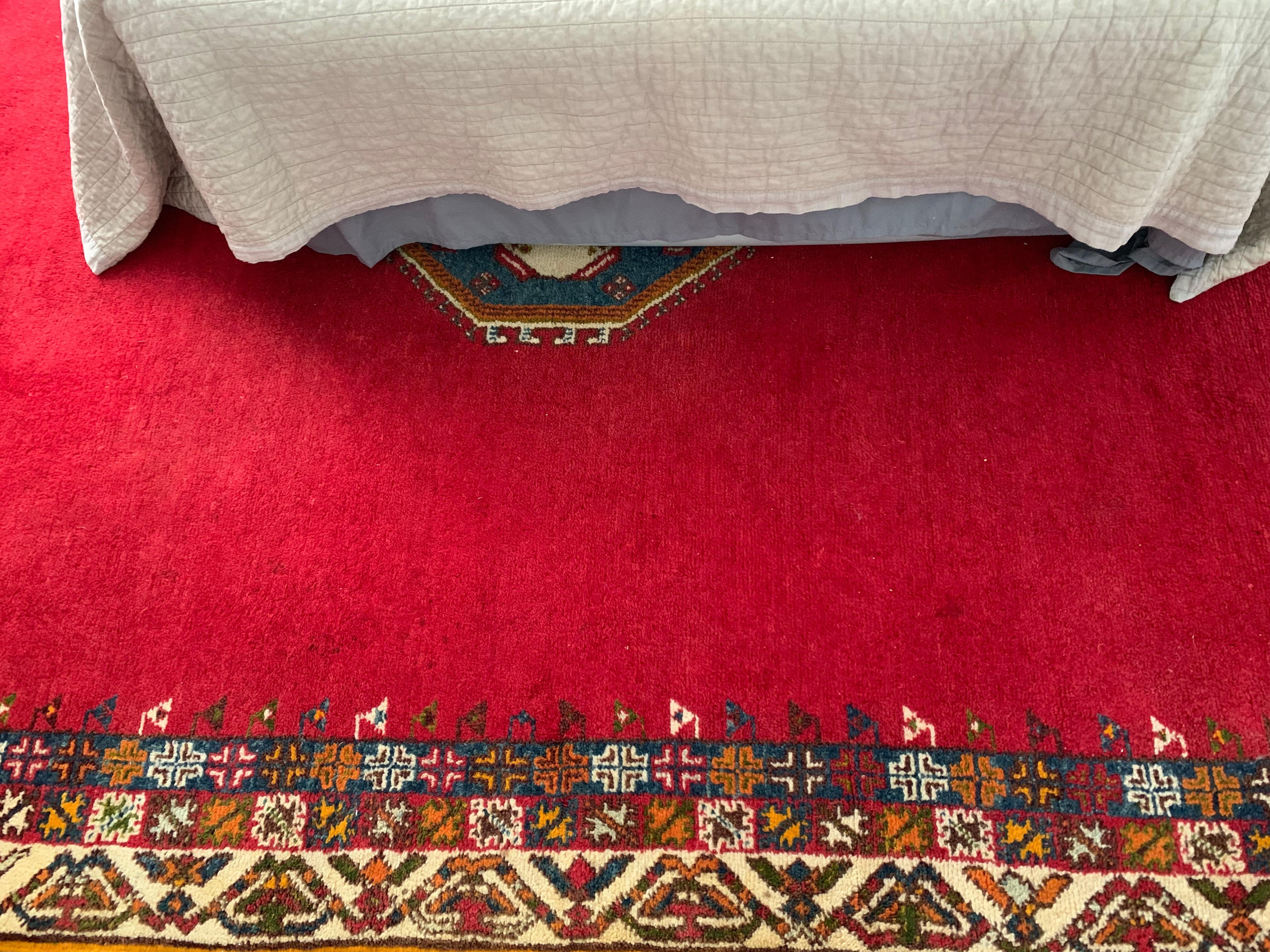 A vibrant red moroccan handmade wool carpet.  Berber people, known for their nomadic lifestyle, pass down the art of weaving through generations, with each tribe having it's distinct style, patterns, and techniques. Berber rugs often feature