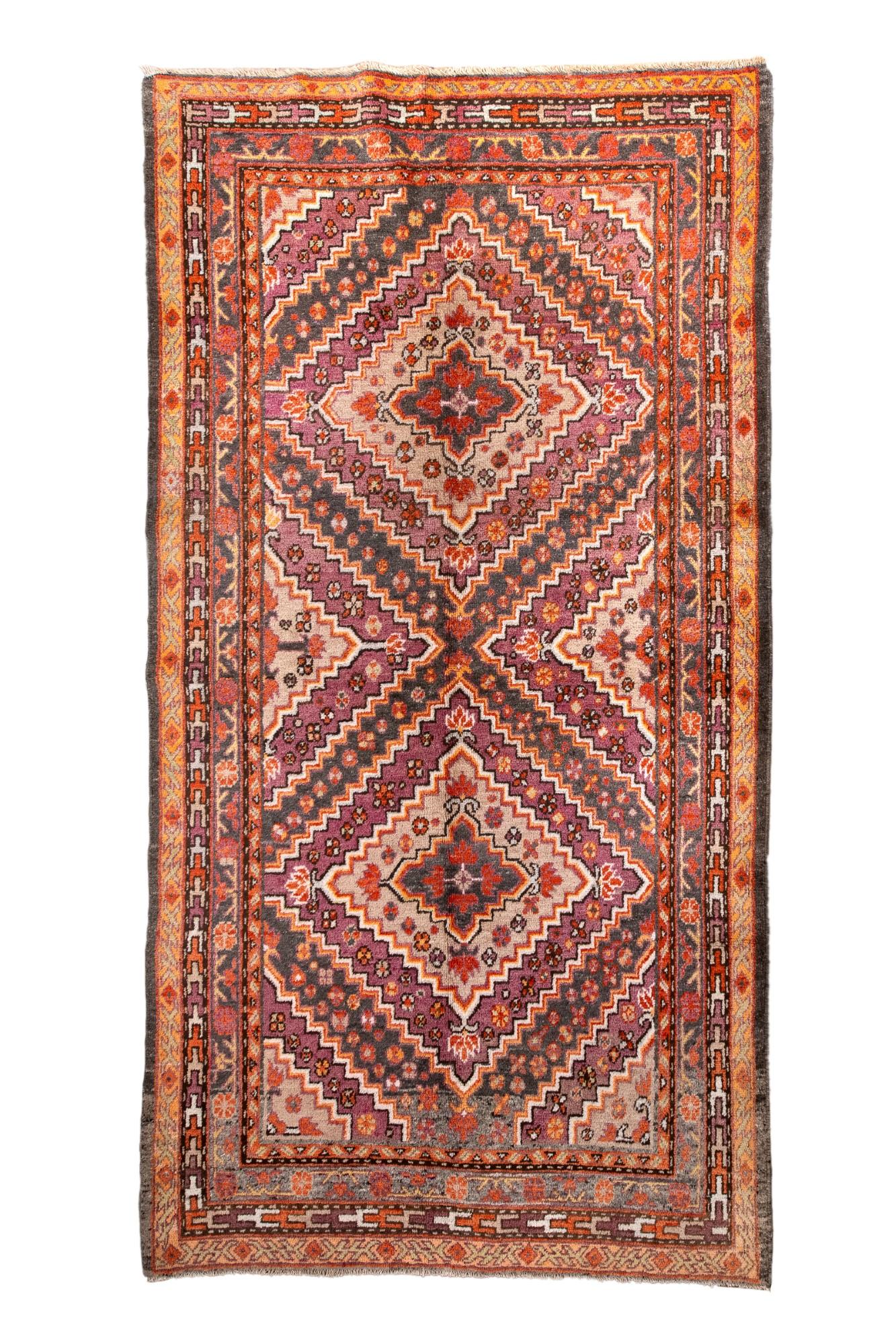 Questo antico tappeto Khotan presenta un classico disegno a medaglioni a gradini in una sorprendente tavolozza di rosso, melanzana, grigio e avorio. Rosette floreali e piccoli motivi geometrici arricchiscono il campo, mentre i tradizionali bordi