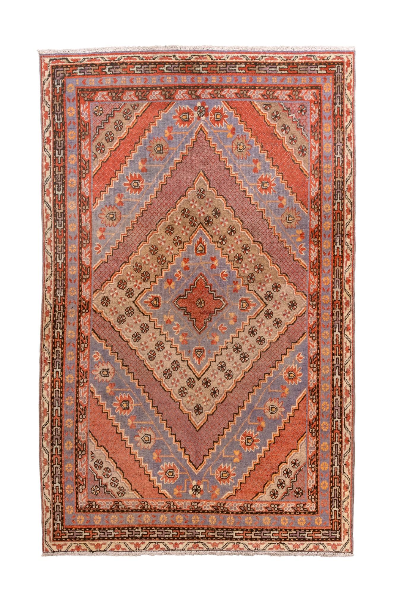 Questo antico tappeto Khotan presenta un sorprendente disegno a medaglioni di diamanti a più livelli, reso in una raffinata tavolozza di lavanda, terracotta, albicocca, taupe e ruggine tenue. I motivi a diamante a gradini, una delle tradizioni più