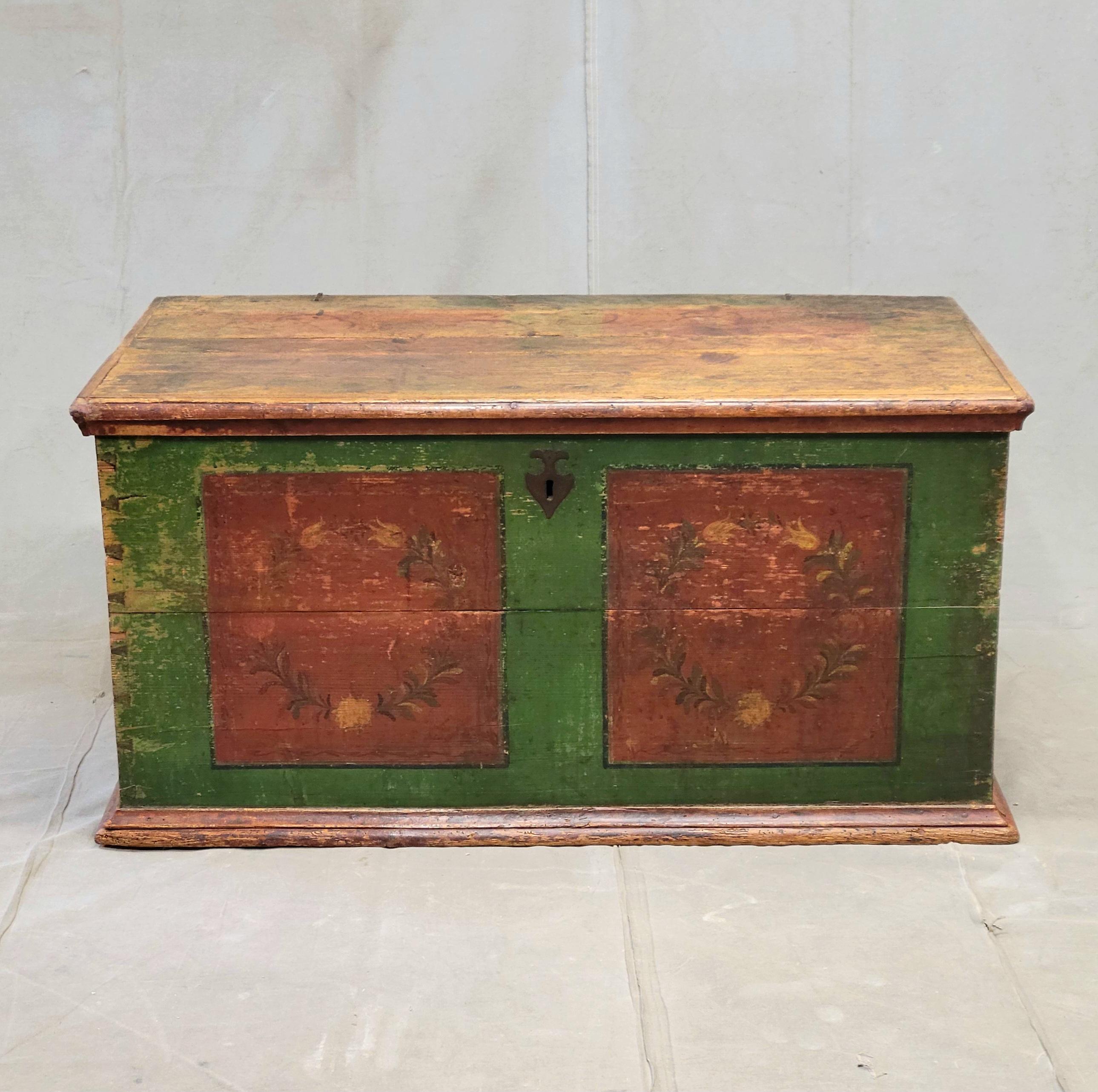 Una splendida cassapanca rustica in pino dell'Europa orientale con vernice originale verde intenso e rosso mattone, probabilmente proveniente dalla Repubblica Ceca e risalente alla fine del 1800. Motivi floreali e ghirlande di foglie impreziosiscono