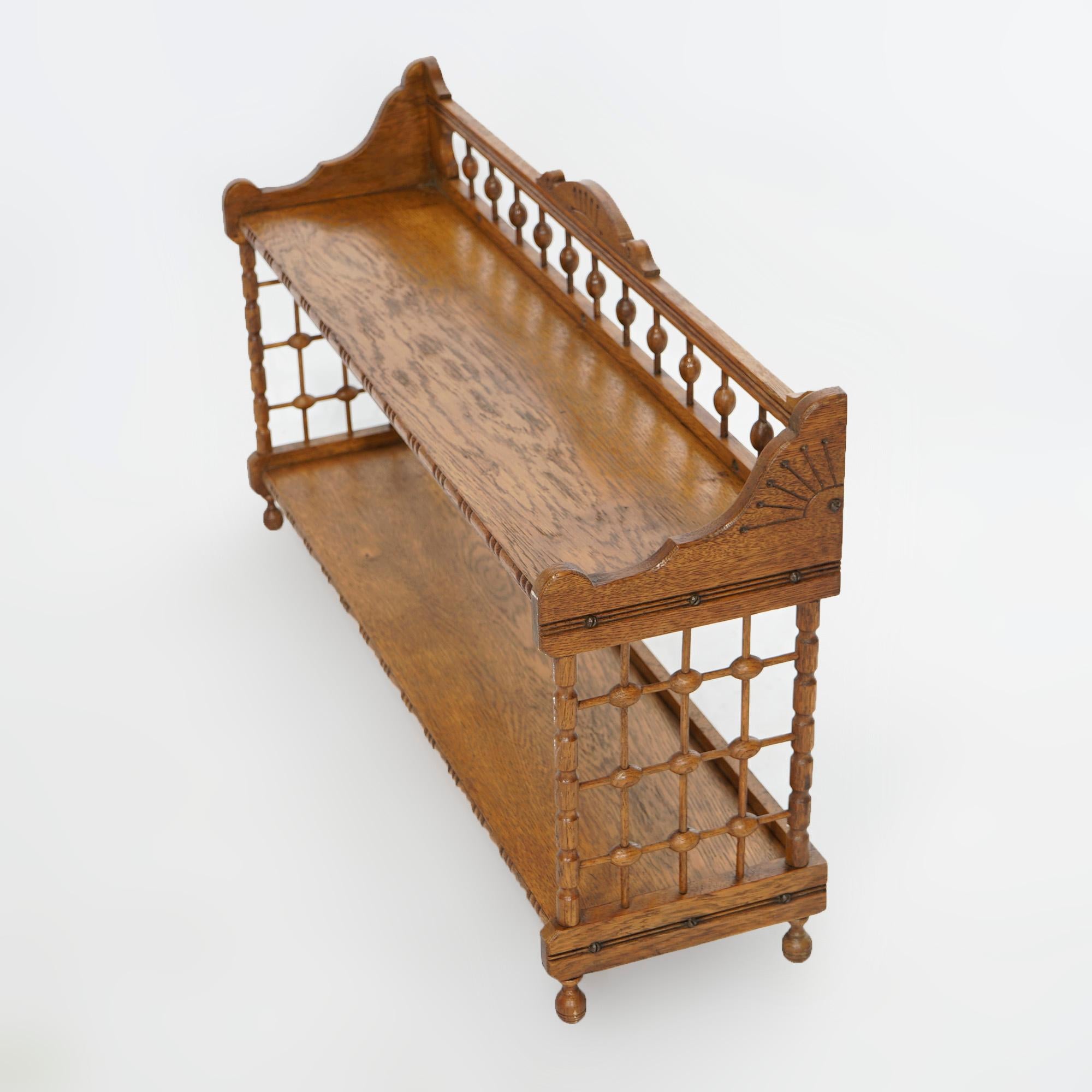 An antique Eastlake hanging wall shelf offers oak construction with stick and ball gallery and sides, crest with incised sunburst decoration and two shelves, c1900

Measures- 19.5'' H x 35.75'' W x 10'' D.

Catalogue Note: Ask about DISCOUNTED