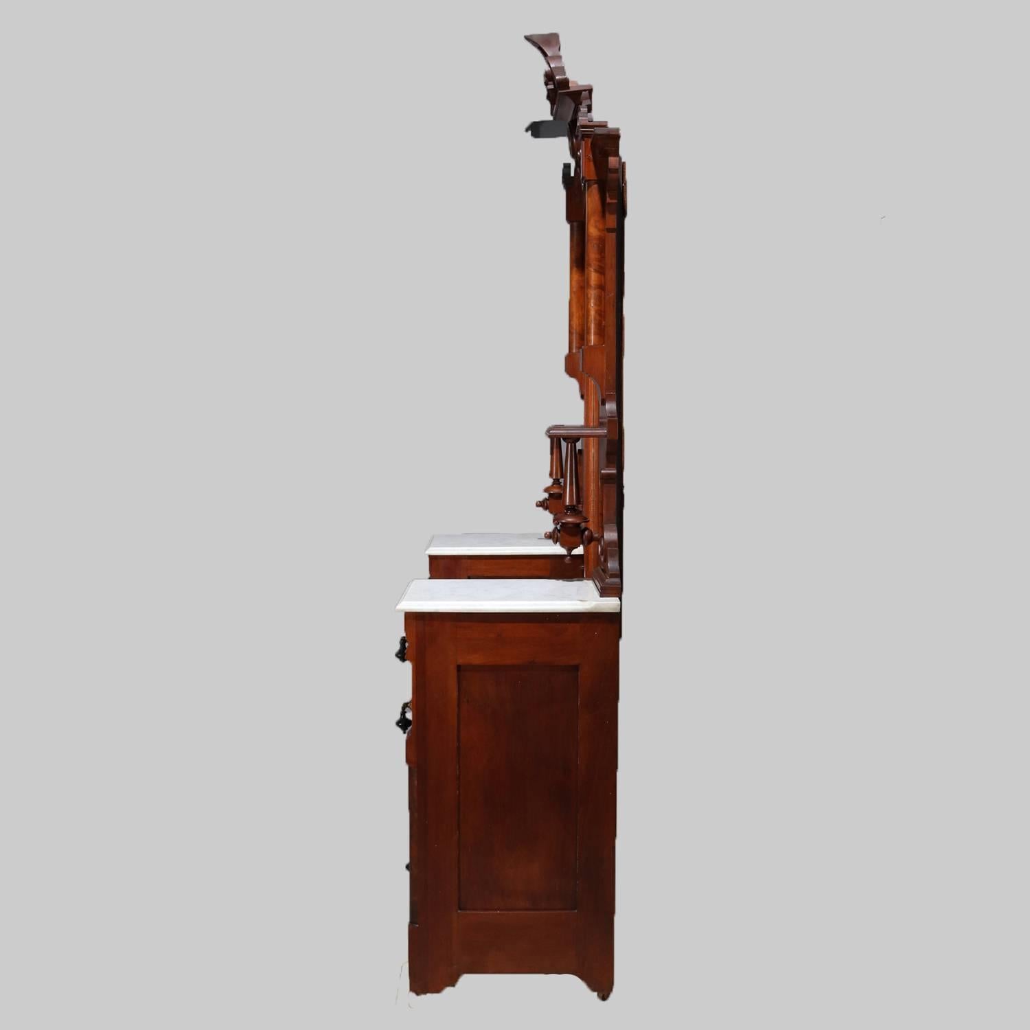 Antique Renaissance Revival carved dresser features carved fleur-de-lis crest over arched tall dressing mirror flanked by candle stands over marble top petite drawers with central sunken marble top over set of long drawers, circa 1890.

Measures: