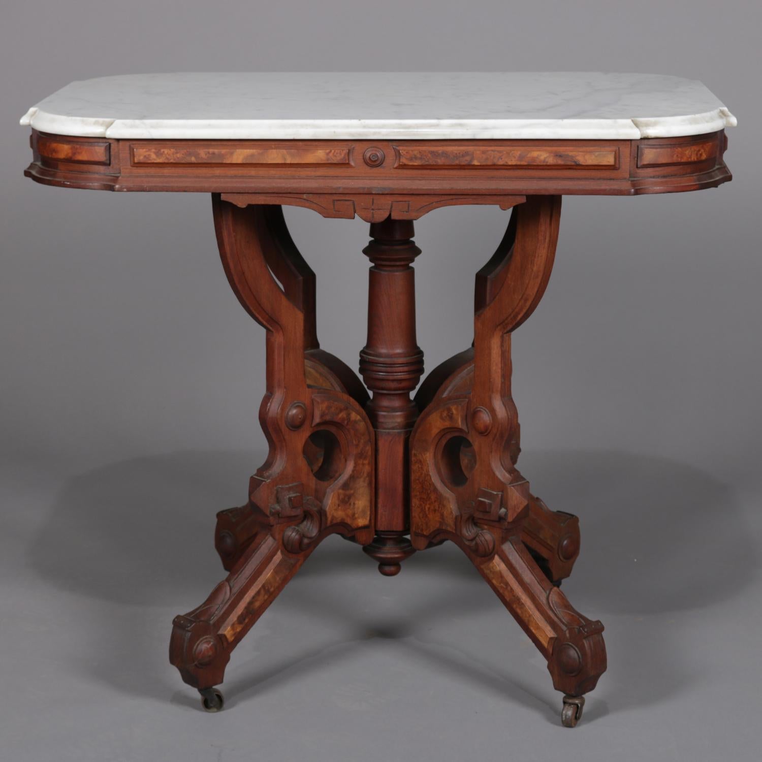 Antique Victorian Eastlake centre table features rectangular clip-corner form with bevelled marble top surmounting carved walnut base having carved apron with burl inset over central turned pedestal and surround of four legs with burl and on