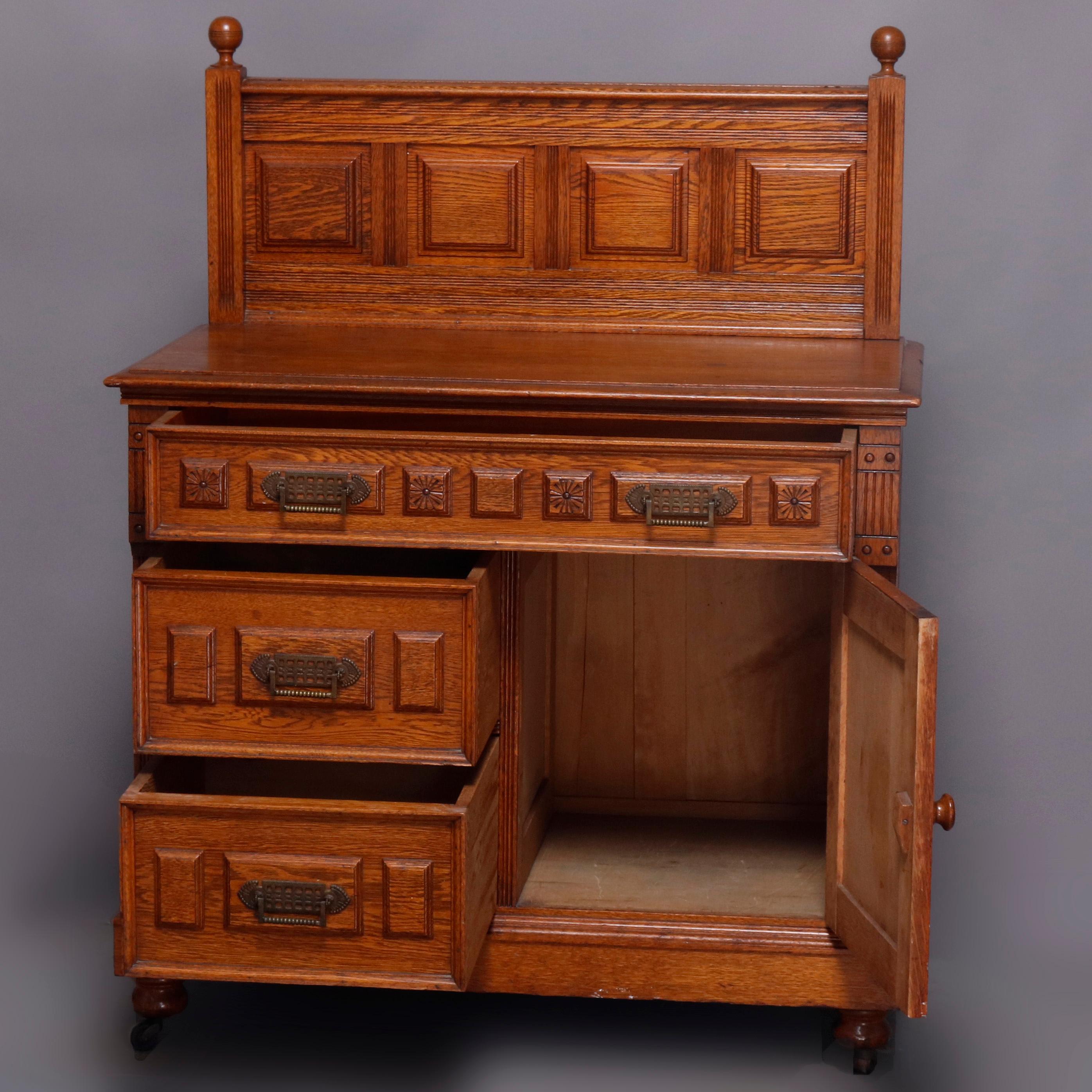 An antique Eastlake wash stand offers carved and paneled oak construction with backsplash having ball finials surmounting lower case with upper long drawer over two smaller drawers and cabinet, cast bronze pulls throughout, 19th century
Matching