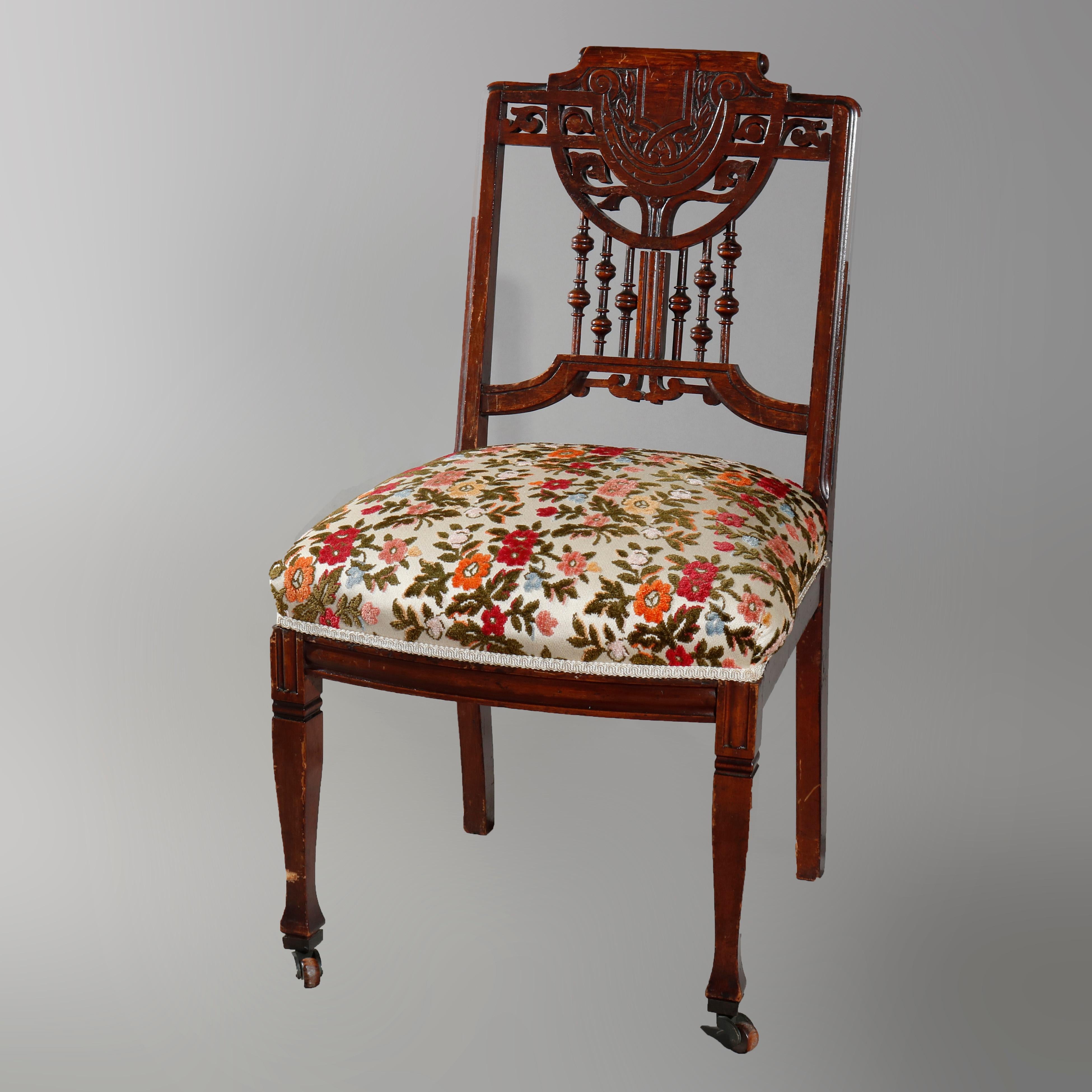 An antique Eastlake parlor set offers mahogany stick and ball frame with chair crest having embossed central shield with flanking scroll and foliate elements, matching settee with pierced cutout scroll frame with demilune upholstered back and scroll