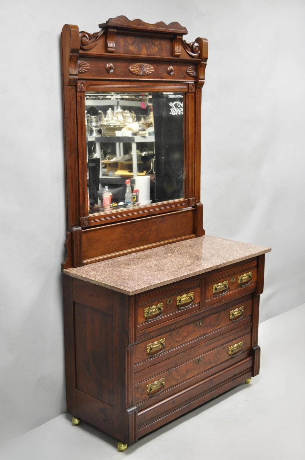 Antique Eastlake Victorian Burl Walnut Marble Top Washstand Dresser w/ Pivoting Beveled Glass Mirror. Item features (4) dovetailed drawers, original brass hardware, working lock and key, raised on rolling castors. Circa Late 19th Century.