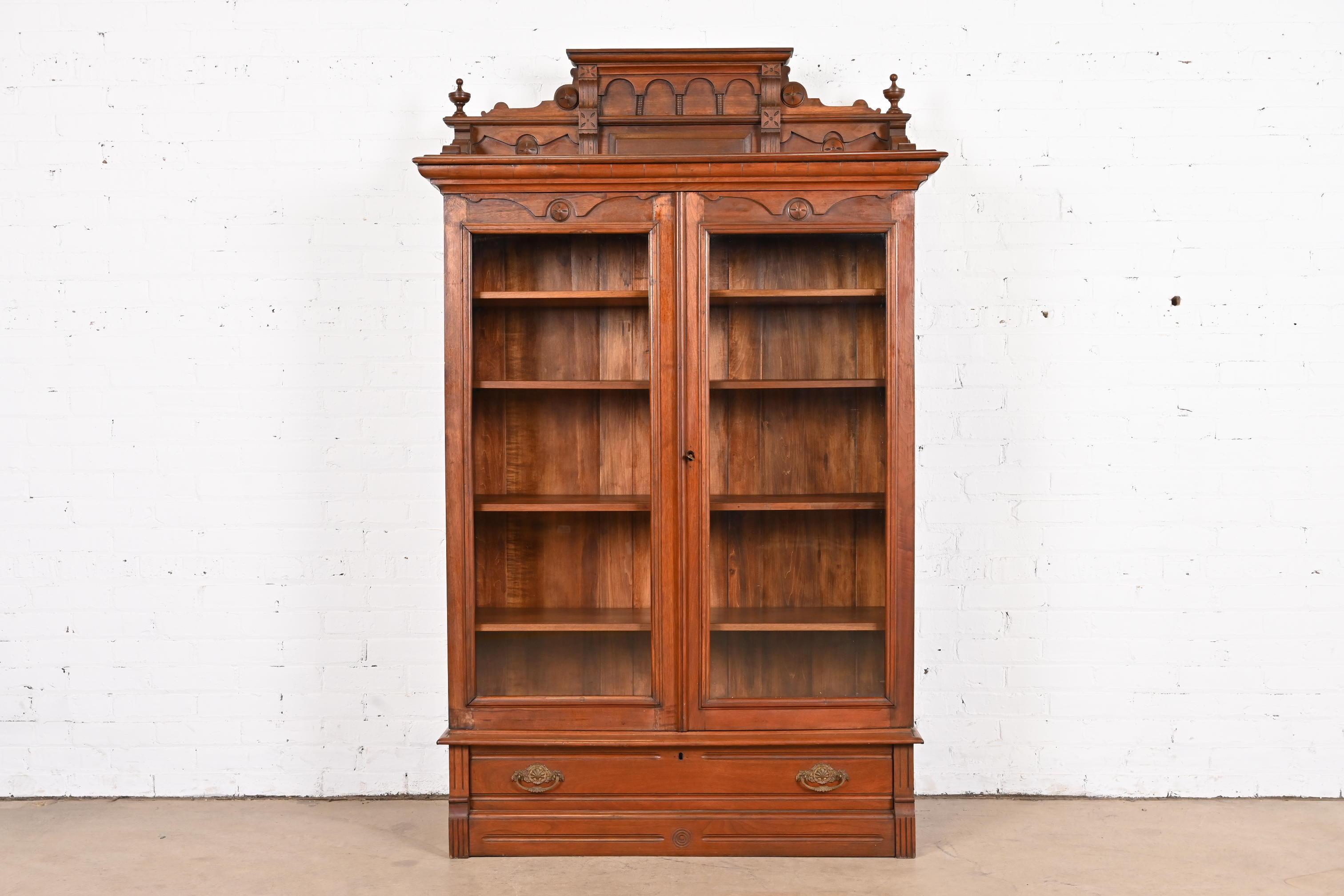 An outstanding antique Eastlake Victorian bookcase cabinet

In the manner of Herter Brothers

USA, circa 1860s

Carved walnut, with glass front doors and brass hardware.

Measures: 45.5