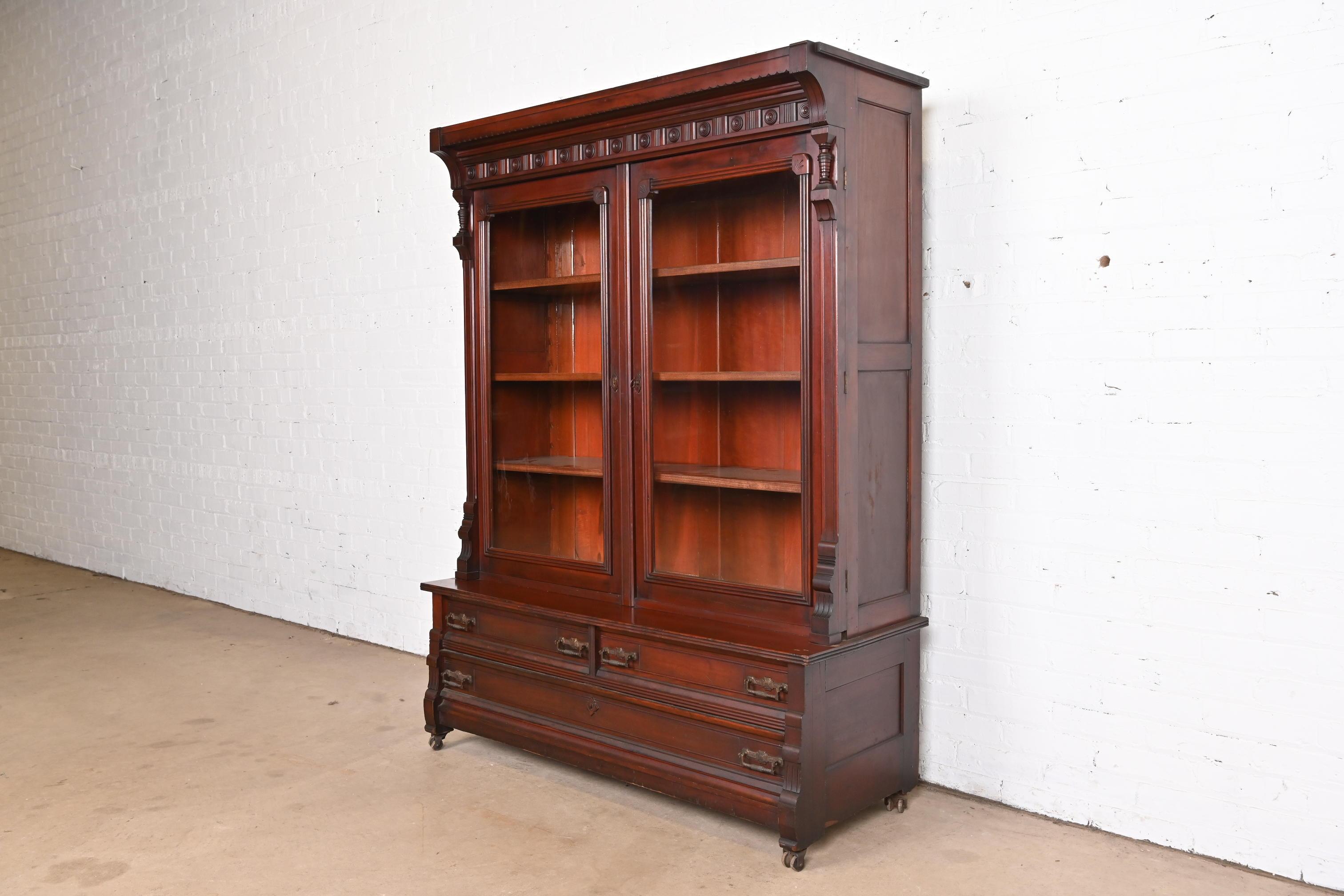 An outstanding antique Eastlake Victorian bookcase cabinet

In the manner of Herter Brothers

USA, Circa 1860s

Carved walnut, with glass front doors and original brass hardware.

Measures: 49.75