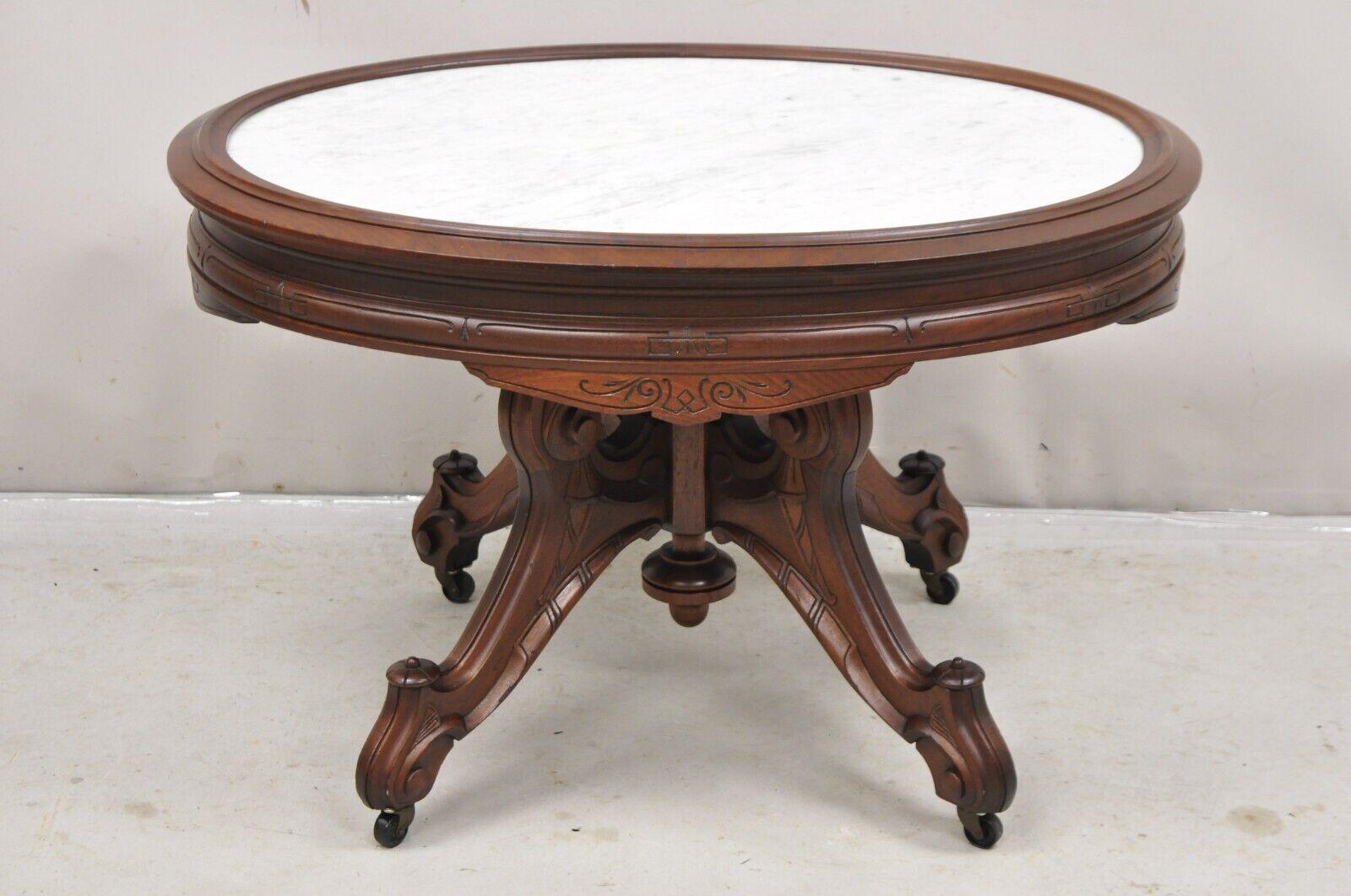 Antique Eastlake Victorian Carved Walnut Oval Marble Top Parlor Coffee Table. Item features an inset white marble top with carved walnut raised edge, rolling casters, carved pedestal base, very nice antique table. Possibly custom made but