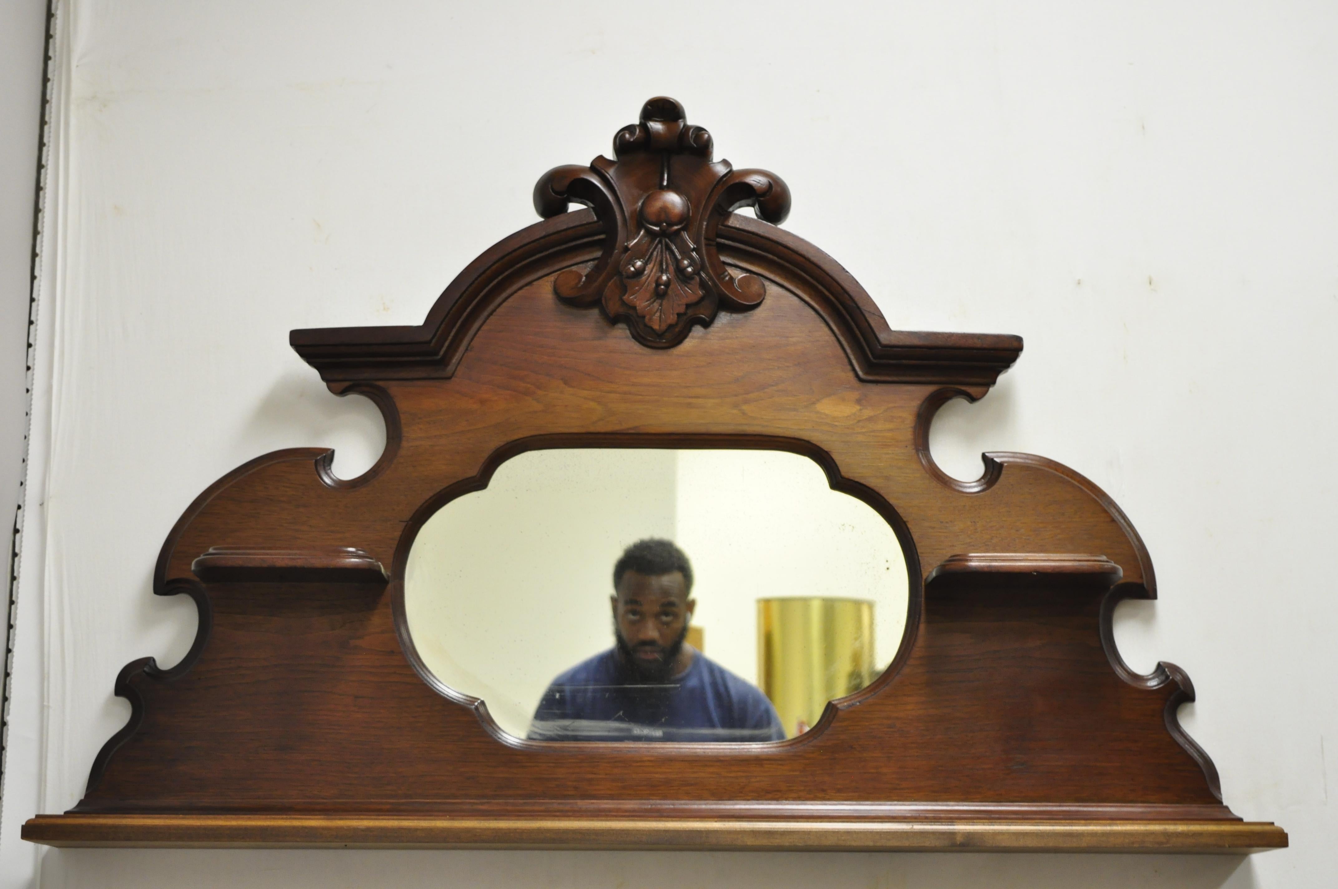 Antique Eastlake Victorian carved walnut wall hanging mirror wall shelf display. Item features unique wall hanging mirror with shelves, solid wood frame, beautiful wood grain, nicely carved details, 3 wooden shelves, very nice antique item, circa