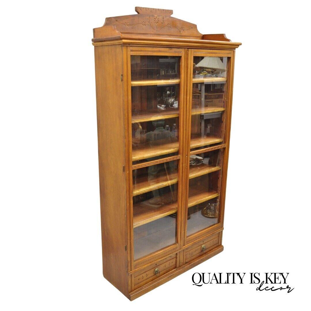 Antique Eastlake Victorian Chestnut 2 Door Bookcase China Cabinet with Drawers. Item features a carved backsplash, 5 adjustable wooden shelves, 2 swing glass doors, 2 drawers, unlocked, no key. Circa 19th century. Measurements: 74.5