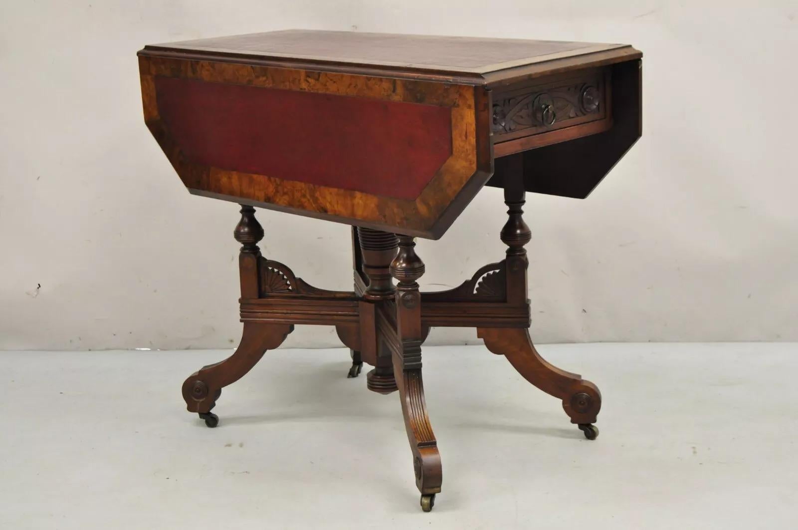 Ancienne table de jeu de salon Eastlake Victorian en noyer avec plateau en cuir. Cet article se caractérise par un socle sculpté, un tiroir à queue d'aronde et un plateau en cuir bordeaux qui s'ouvre et s'allonge en tournant. Table antique très