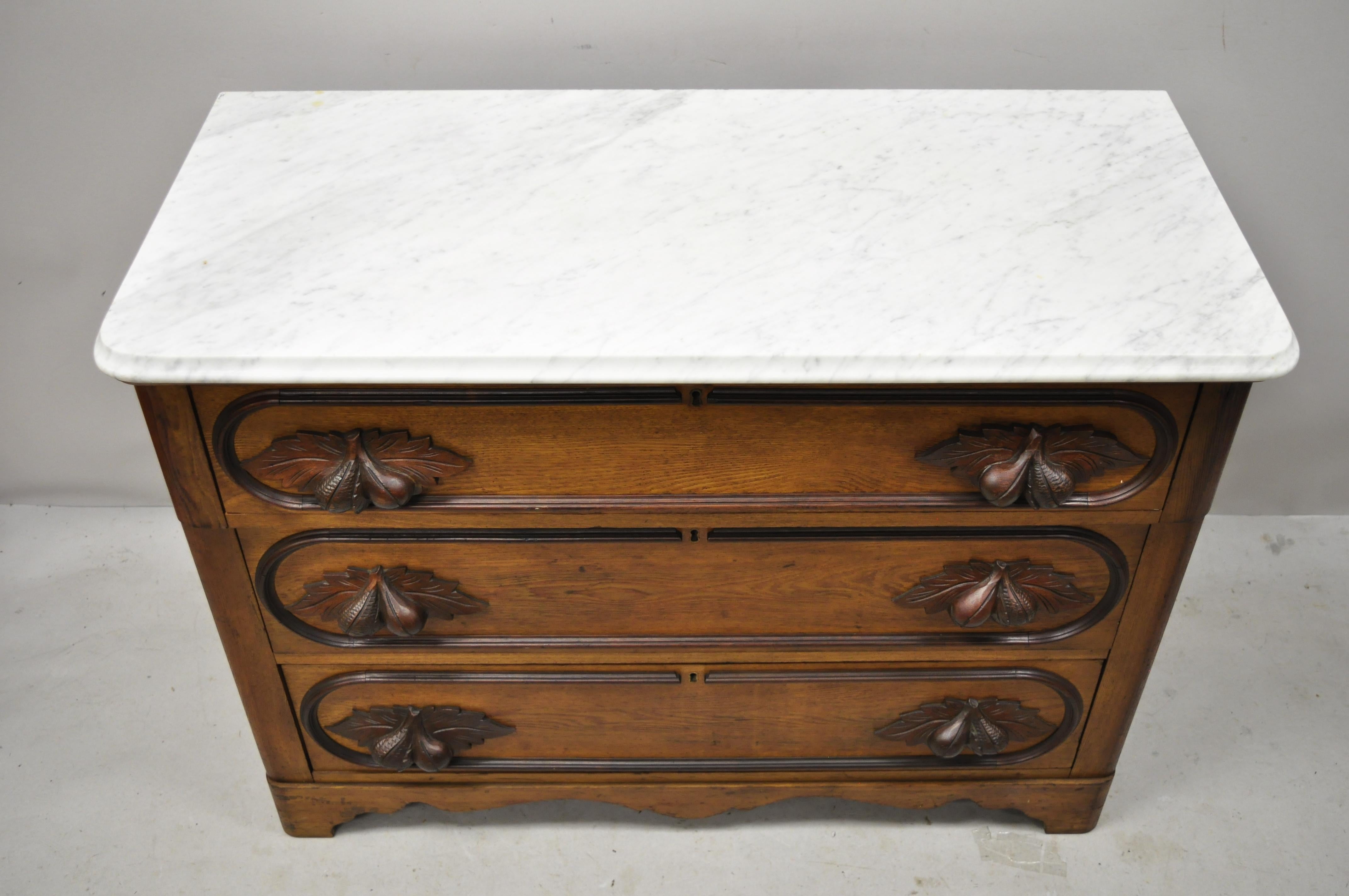 Antique Eastlake Victorian marble-top chestnut dresser with fruit carved pulls. Item features marble top, fruit and maple leaf carved drawer pulls, beautiful wood grain, no key, but unlocked, 3 dovetailed drawers, very nice antique item, circa late