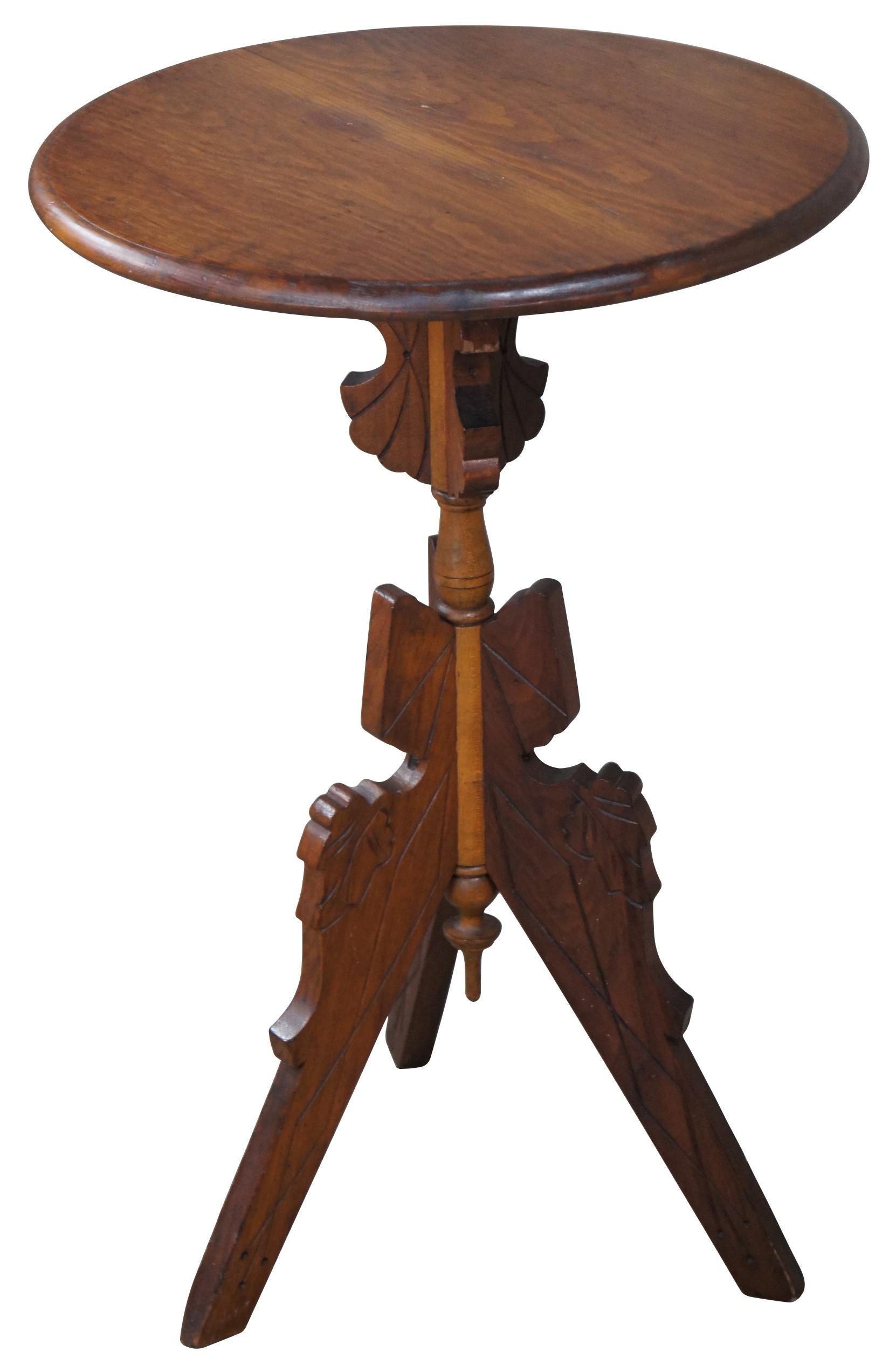 Antique Eastlake Victorian round oak parlor pedestal table featuring a tripod base with carved leaves and drop finial.
 