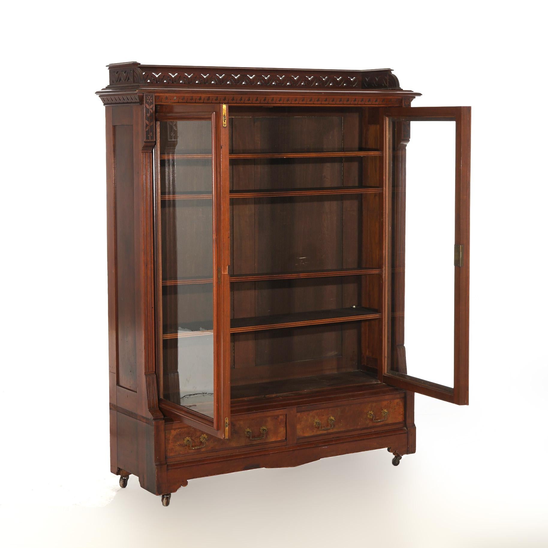 ***Ask About Reduced In-House Shipping Rates - Reliable Service & Fully Insured***
An antique Eastlake bookcase offers walnut and burl construction with pierced gallery over case with double glass doors opening to adjustable shelf interior seated on