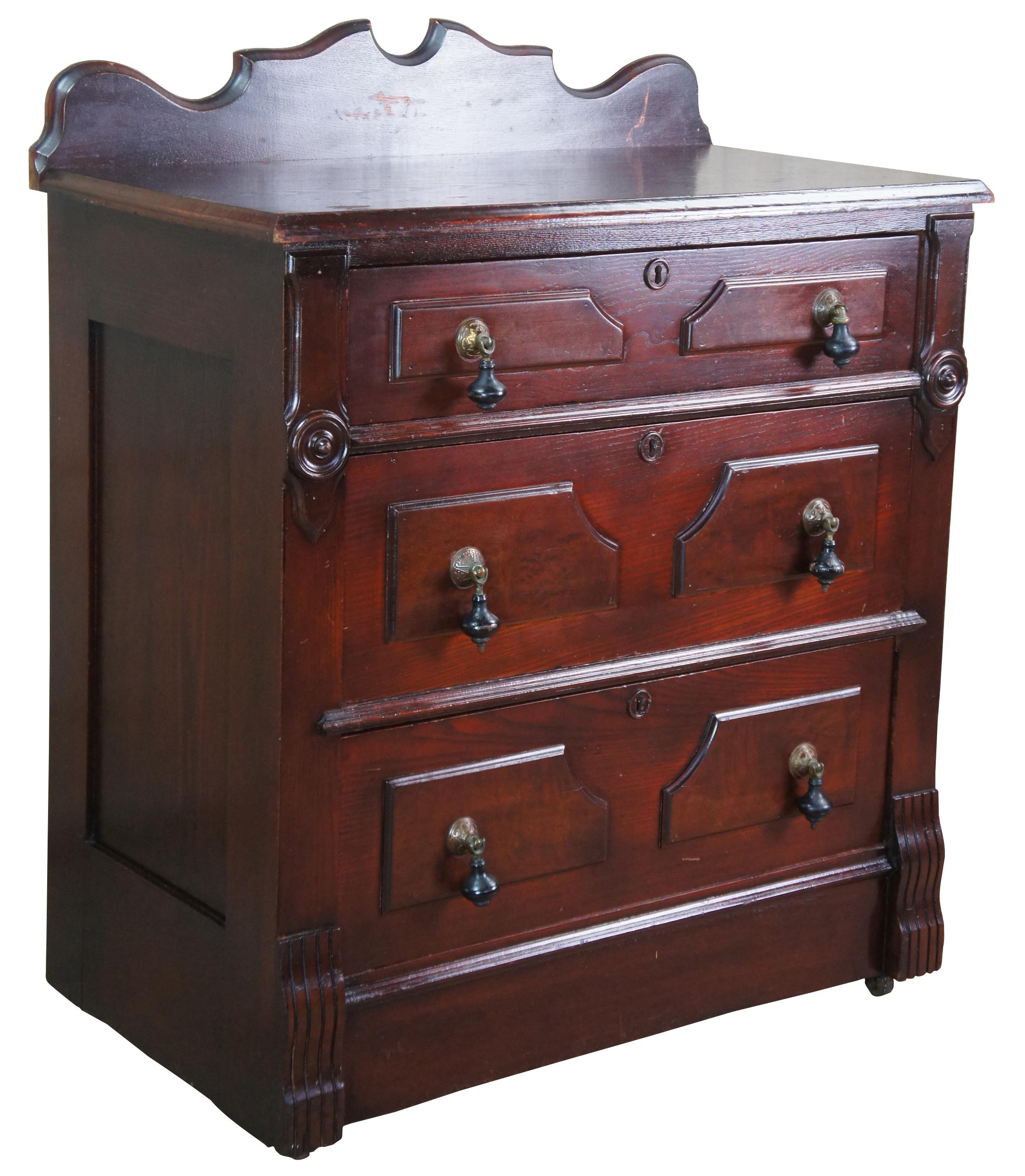 Antique Eastlake Victorian parlor washstand or chest. Made of pine featuring three paneled walnut burl drawers with ebonized teardrop pulls with brass rosettes, carved accents, serpentine backsplash and casters.
          