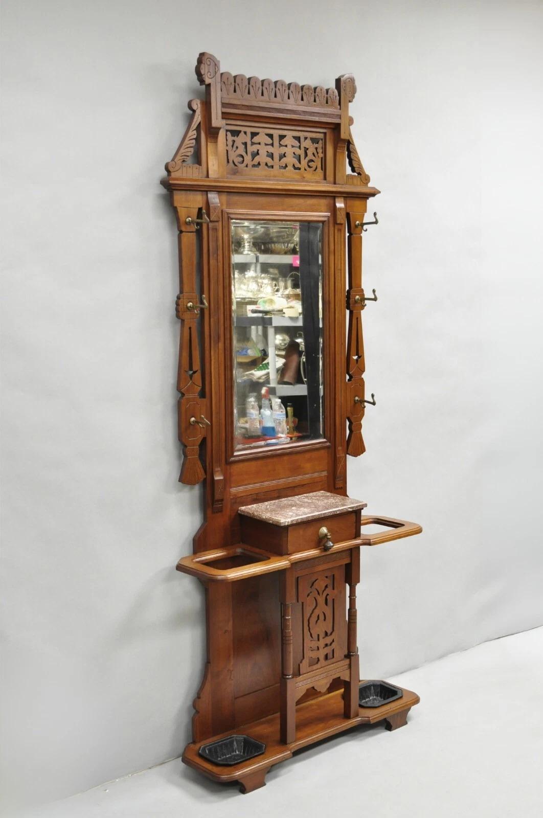 Porte-parapluies victorien ancien Eastlake en noyer avec miroir en verre biseauté et égouttoirs en fonte. Vers la fin du 19e siècle. Dimensions : 89