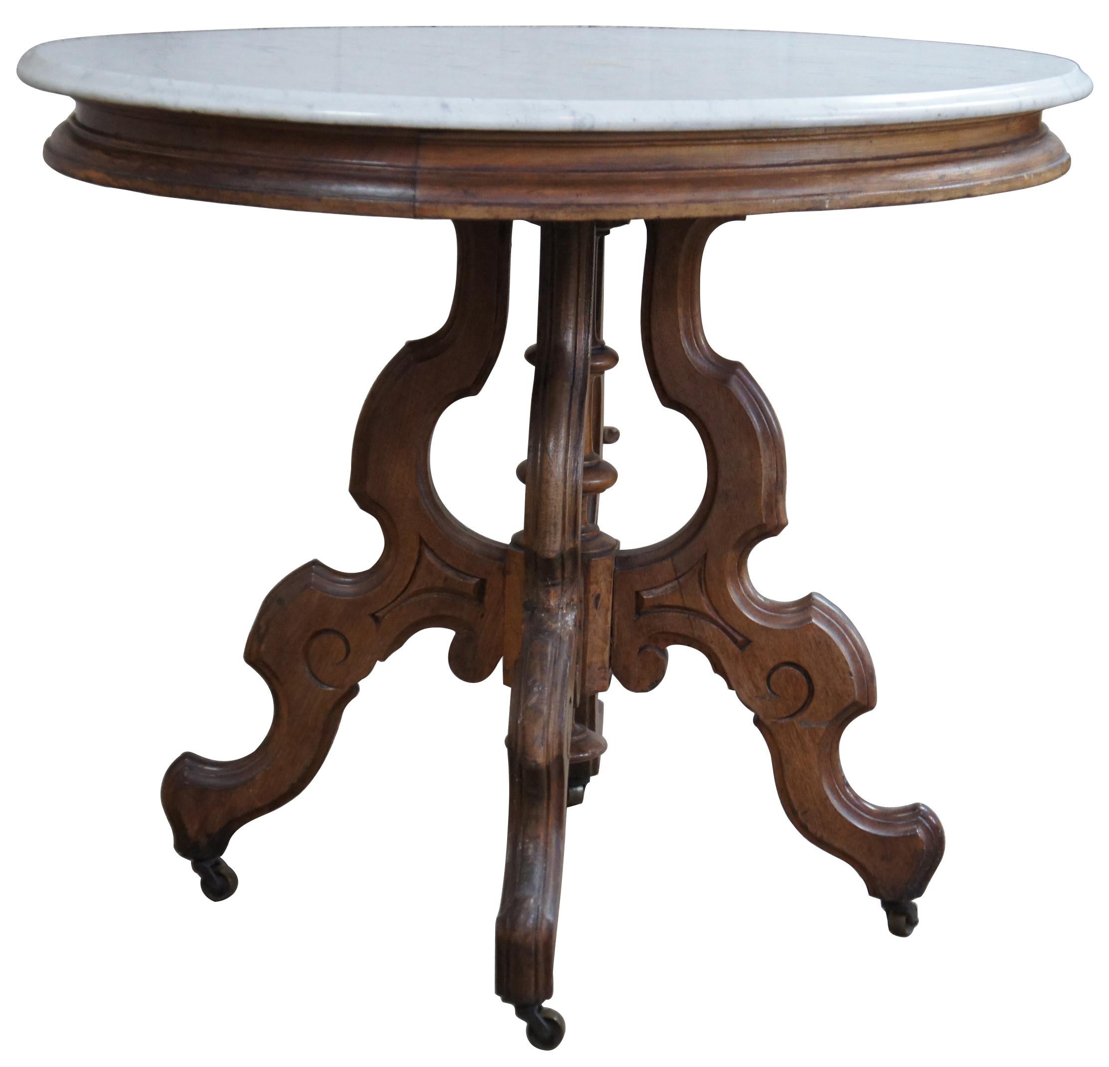Antique Victorian Eastlake parlor table, circa 1880s. Made from walnut with an oval white marble top. Base features a turned center support surrounded by four serpentine carved legs leading to castors. 
  