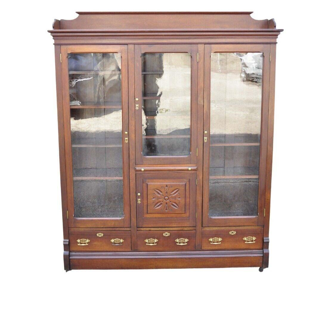 Ancienne Eastlake Victorian Walnut Wavy Glass Triple Bookcase Display Cabinet. L'article comprend 16 étagères en bois réglables (il faut des lattes en bois pour en insérer quatre), 3 tiroirs à queue d'aronde, verre ondulé d'origine, quincaillerie en
