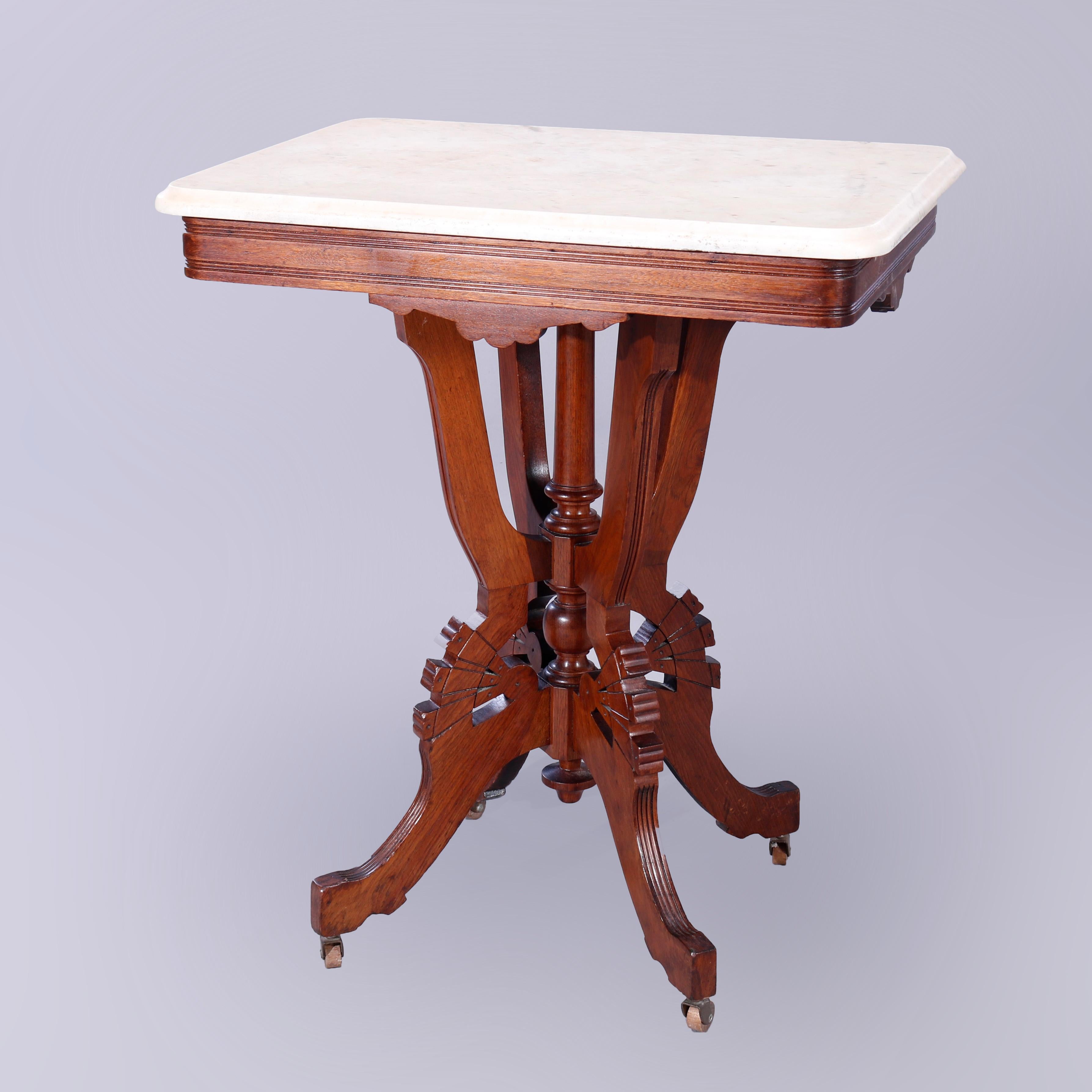 An antique Eastlake parlor table offers beveled rectangular marble top over carved and incised walnut base having burl insets and raised on stylized scroll form legs with central turned column and drop finial, c1890

Measures - 31'' H x 26'' W x