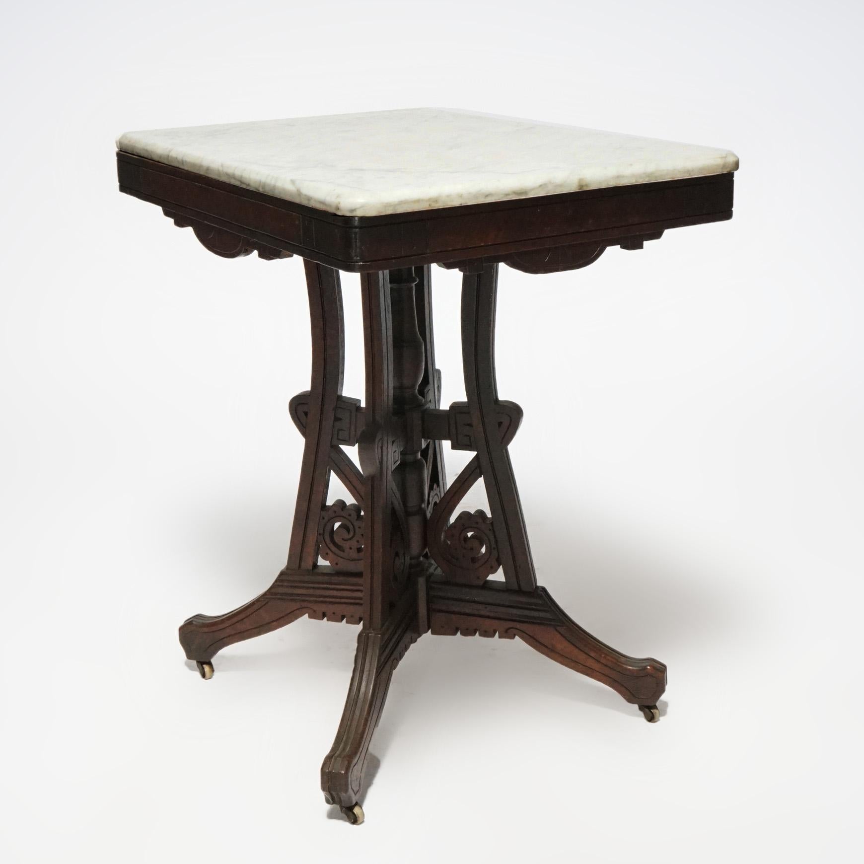 An antique Eastlake parlor table offers beveled marble top over walnut base having shaped skirt with burl insets, four concave supports having scroll form elements and central turned column, incised decoration throughout, c1890.

Measures- 29.5''H x