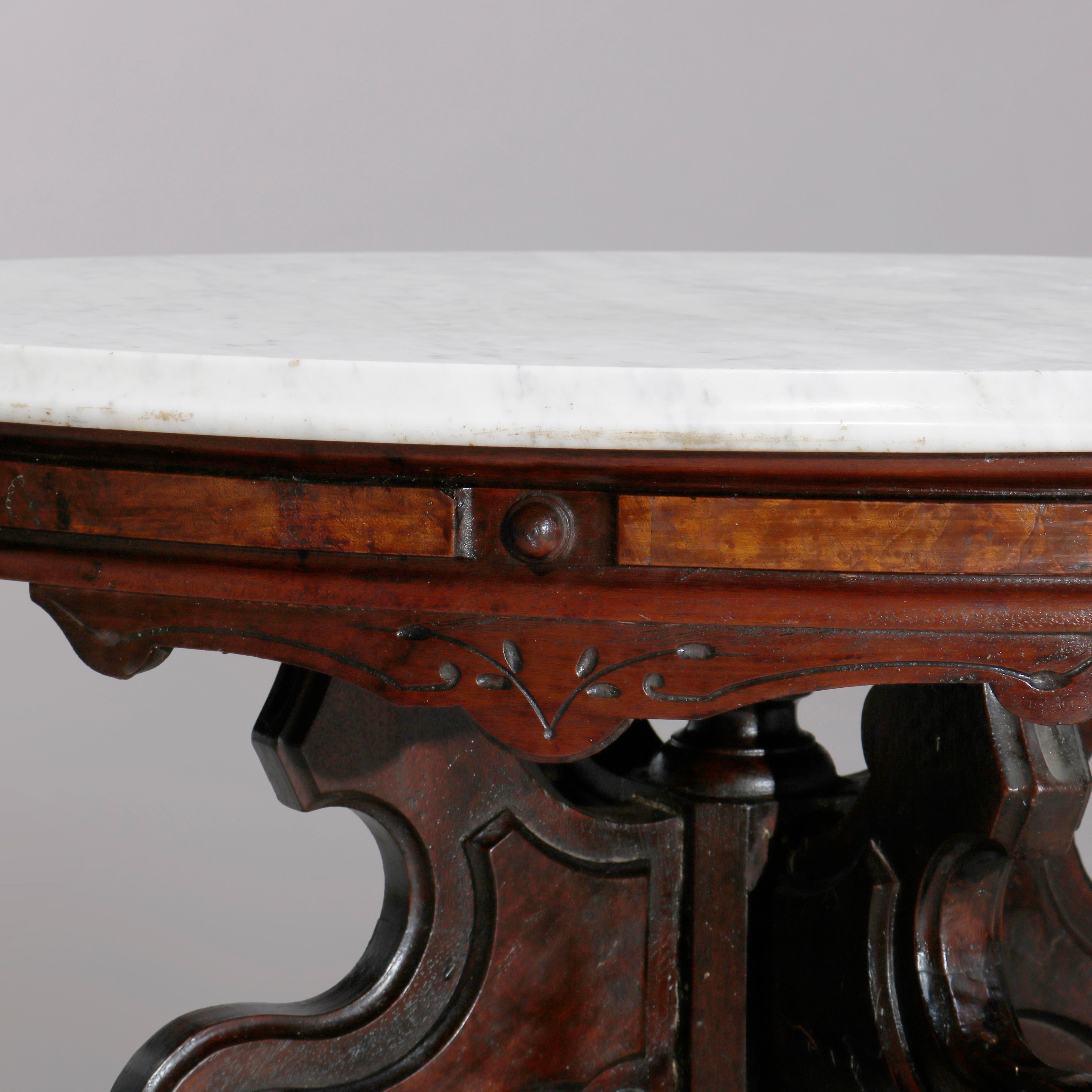 An antique Eastlake low table offers oval beveled marble top surmounting carved walnut and burl base raised on shaped legs with central drop finial, c1890

Measures: 21