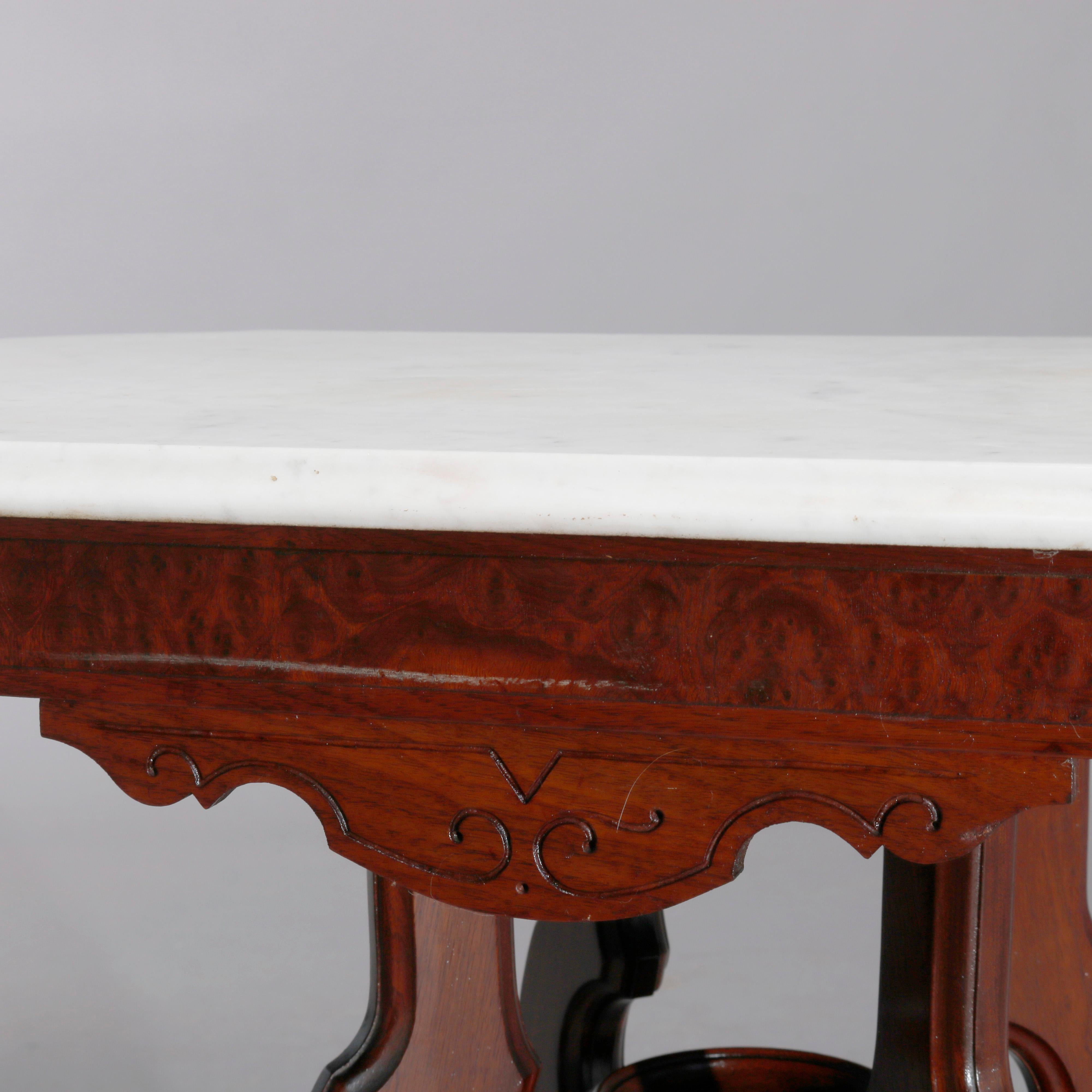 An antique Eastlake center table offers shaped beveled marble top surmounting carved walnut and burl base raised on shaped legs with central urn form finial, c1890.

Measures: 30.25
