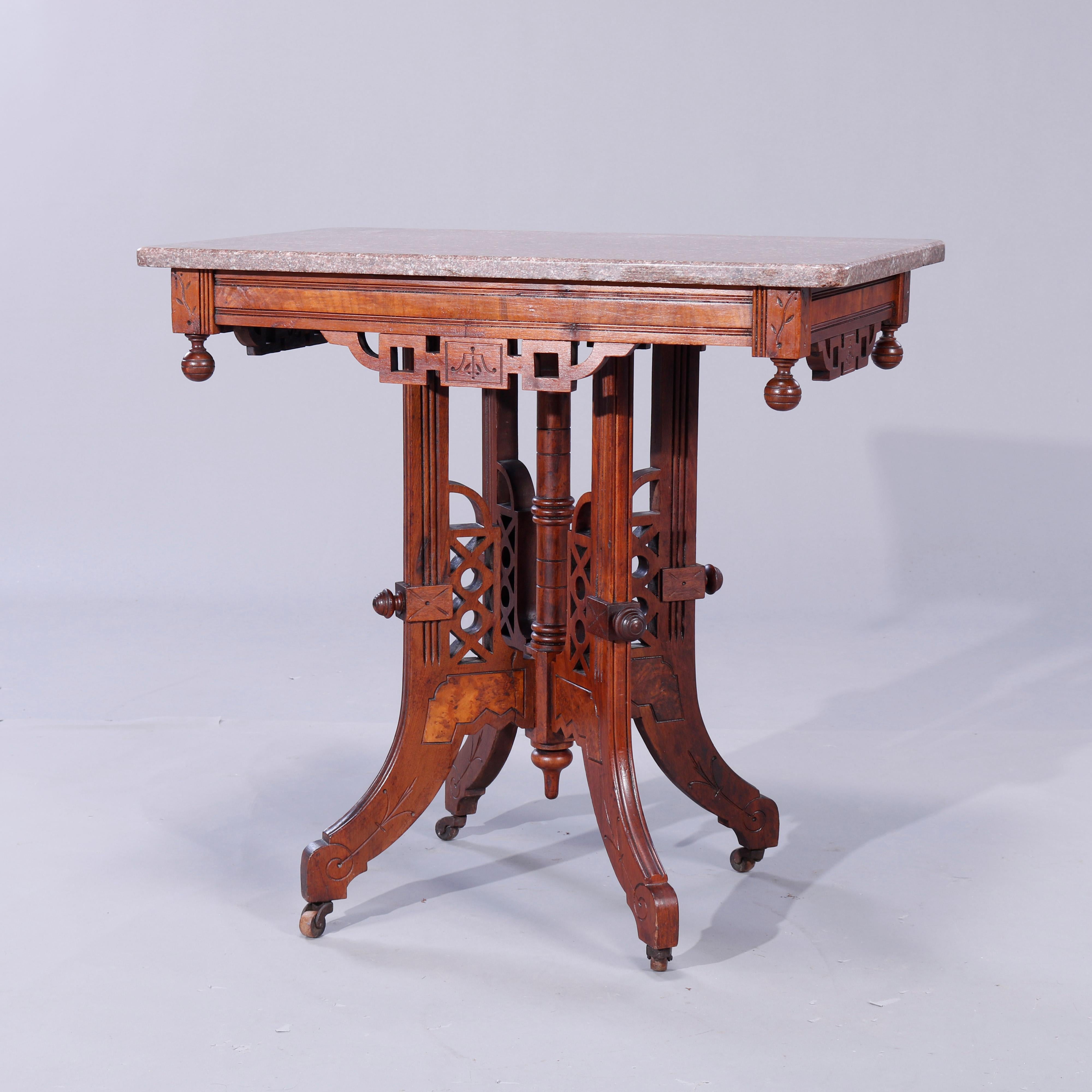 An antique Eastlake parlor table offers rouge marble top over carved walnut base having burl inset, cut-out skirl and drop ball finials raised on legs with cutout design and turned central column, elements reminiscent of Art Deco, c1890

Measures -