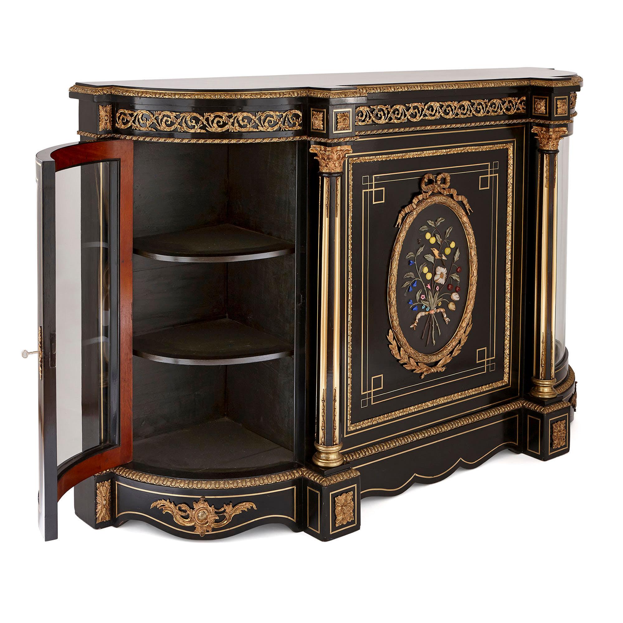 This cabinet is an exquisite piece of antique furniture, which is crafted from beautifully-contrasting ebonised wood, golden gilt bronze (ormolu) and colourful hardstones. 

The cabinet is composed of a wide, bombé-fronted body which is set on
